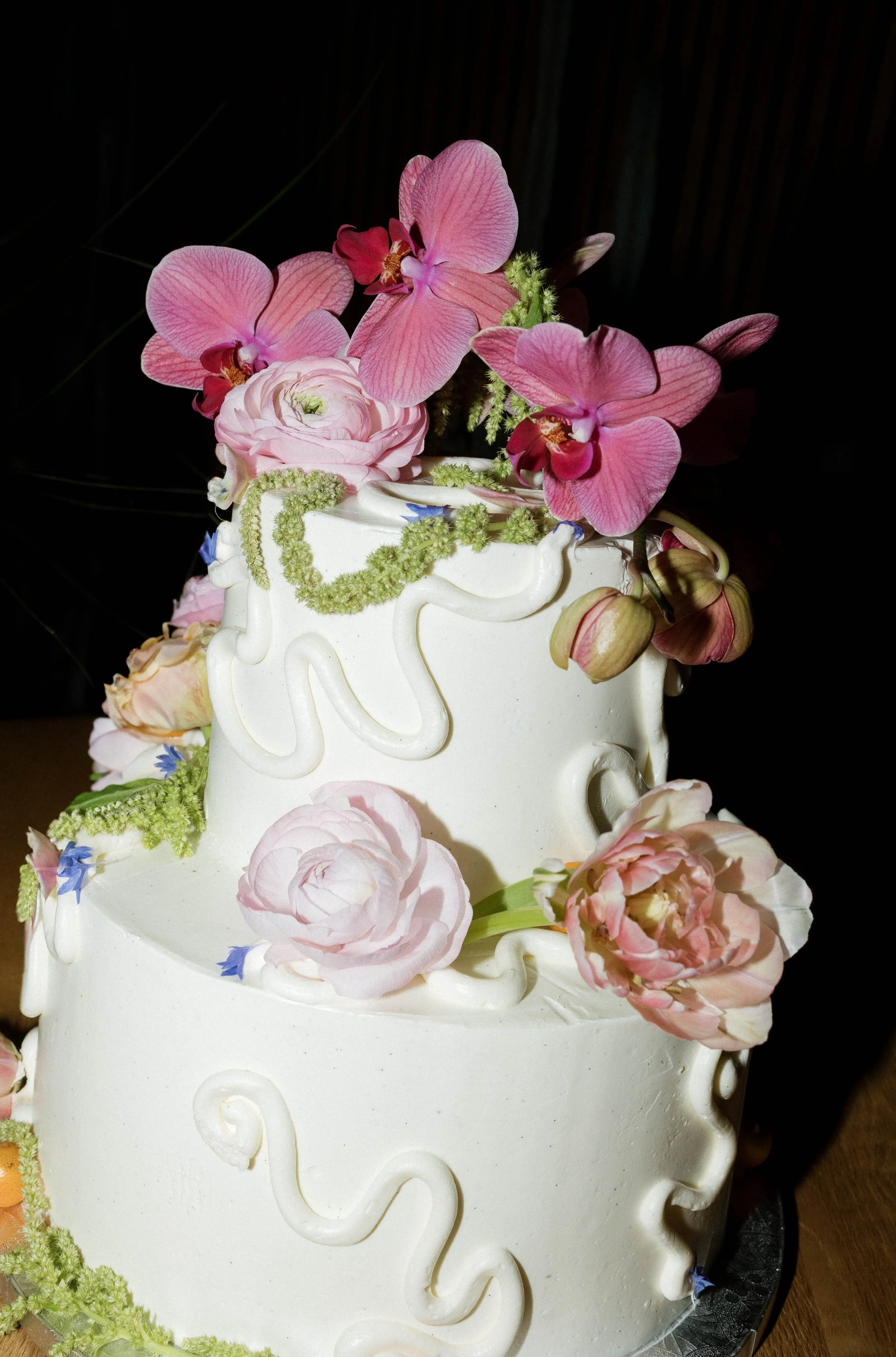 Elegant tiered wedding cake with white icing and floral details at a Southern California wedding reception.