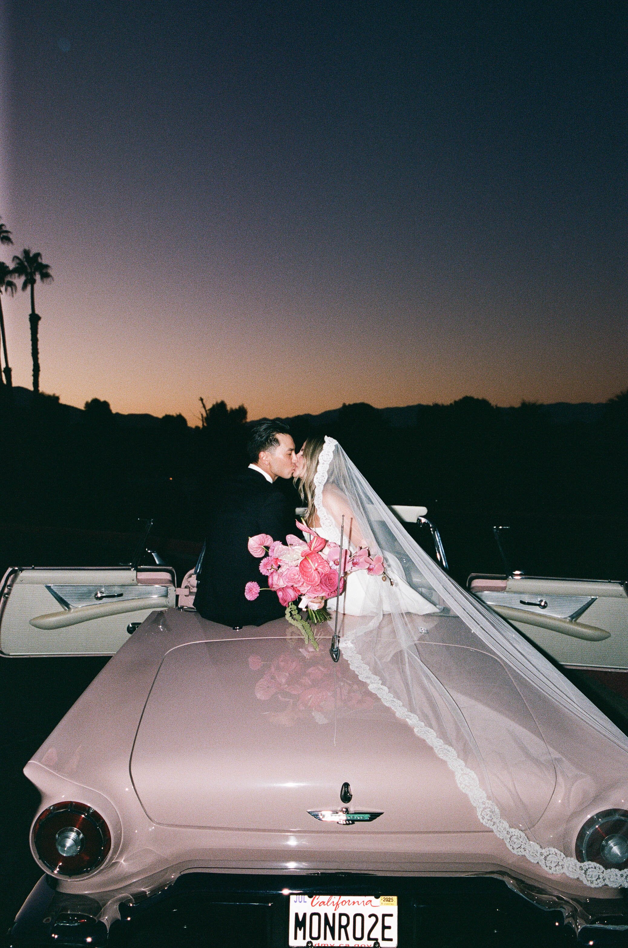 Bride and groom in car at desert wedding.