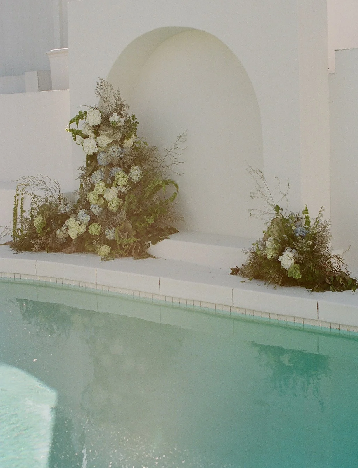 Modern wedding venue with poolside floral installation in California.