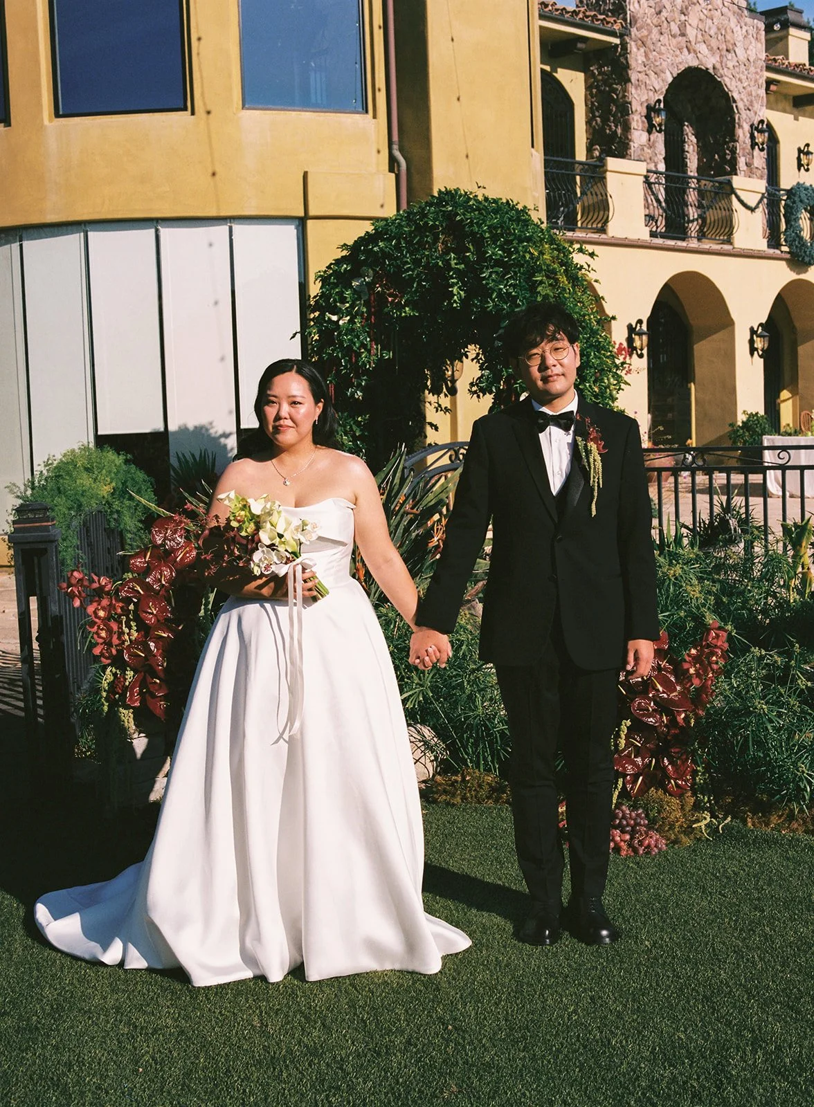 Bride and groom walking through the garden at a private estate wedding designed by a Los Angeles wedding planner.