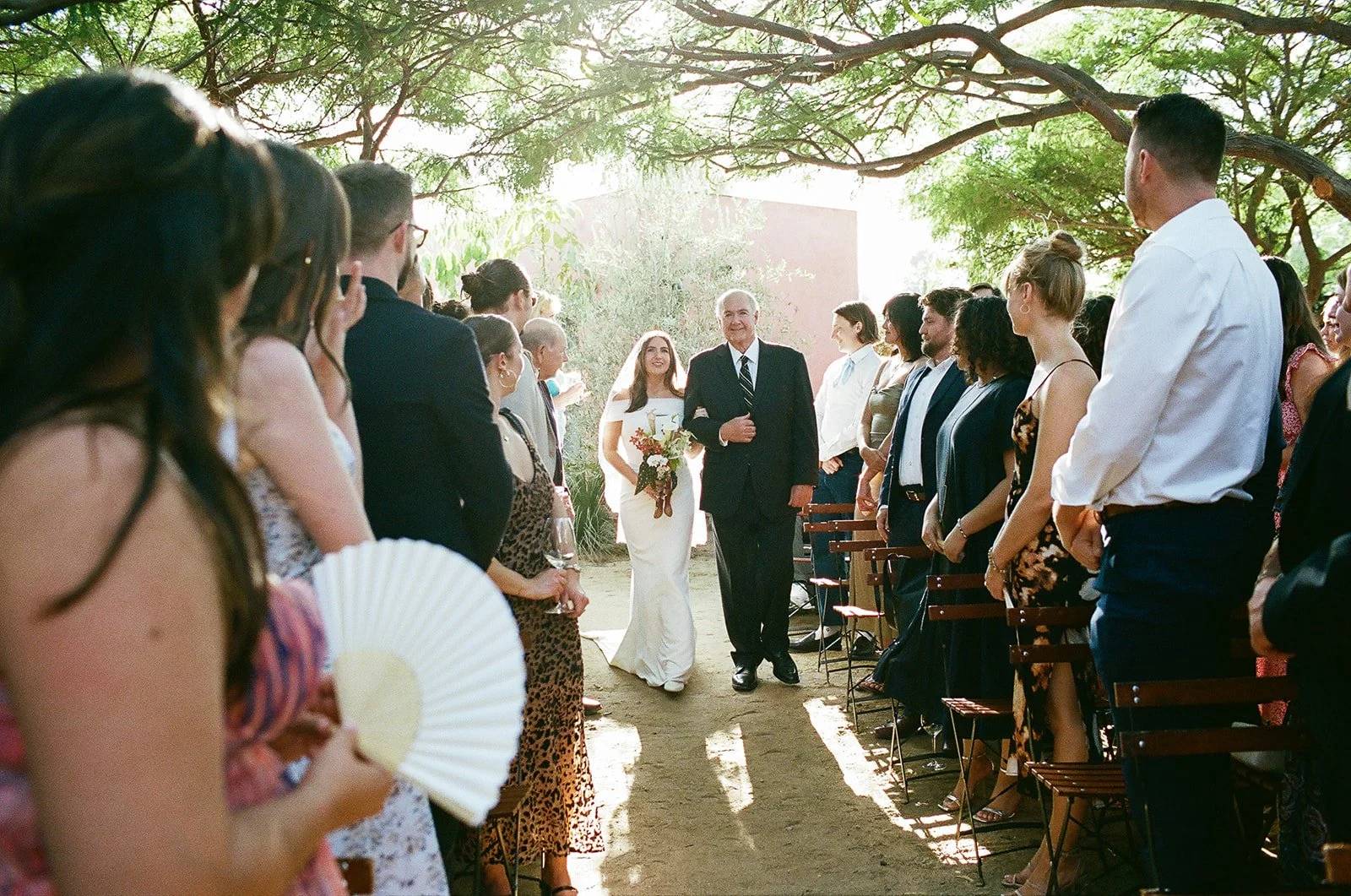 Bride walking down the aisle at an outdoor at ceremony designed by Los Angeles wedding planner. 