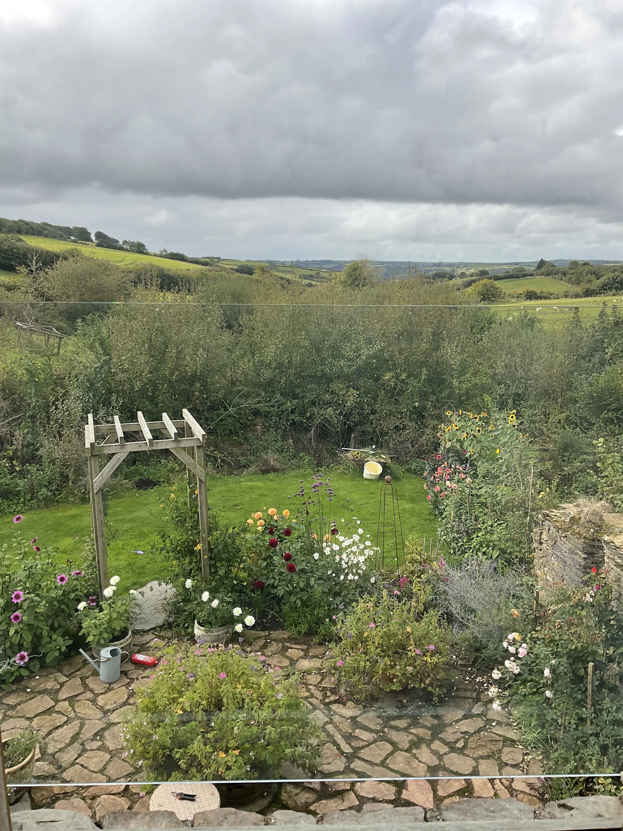 The beautiful view from the house, across the patio and garden full of flowers, towards the Exmoor hills in the distance