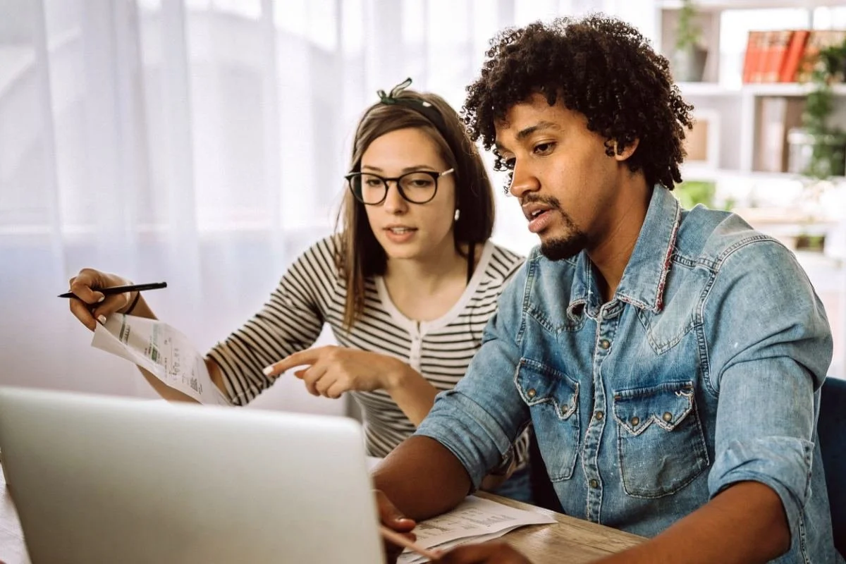 Couple at a desk with a laptop and paperwork, planning the finances for a holiday let property