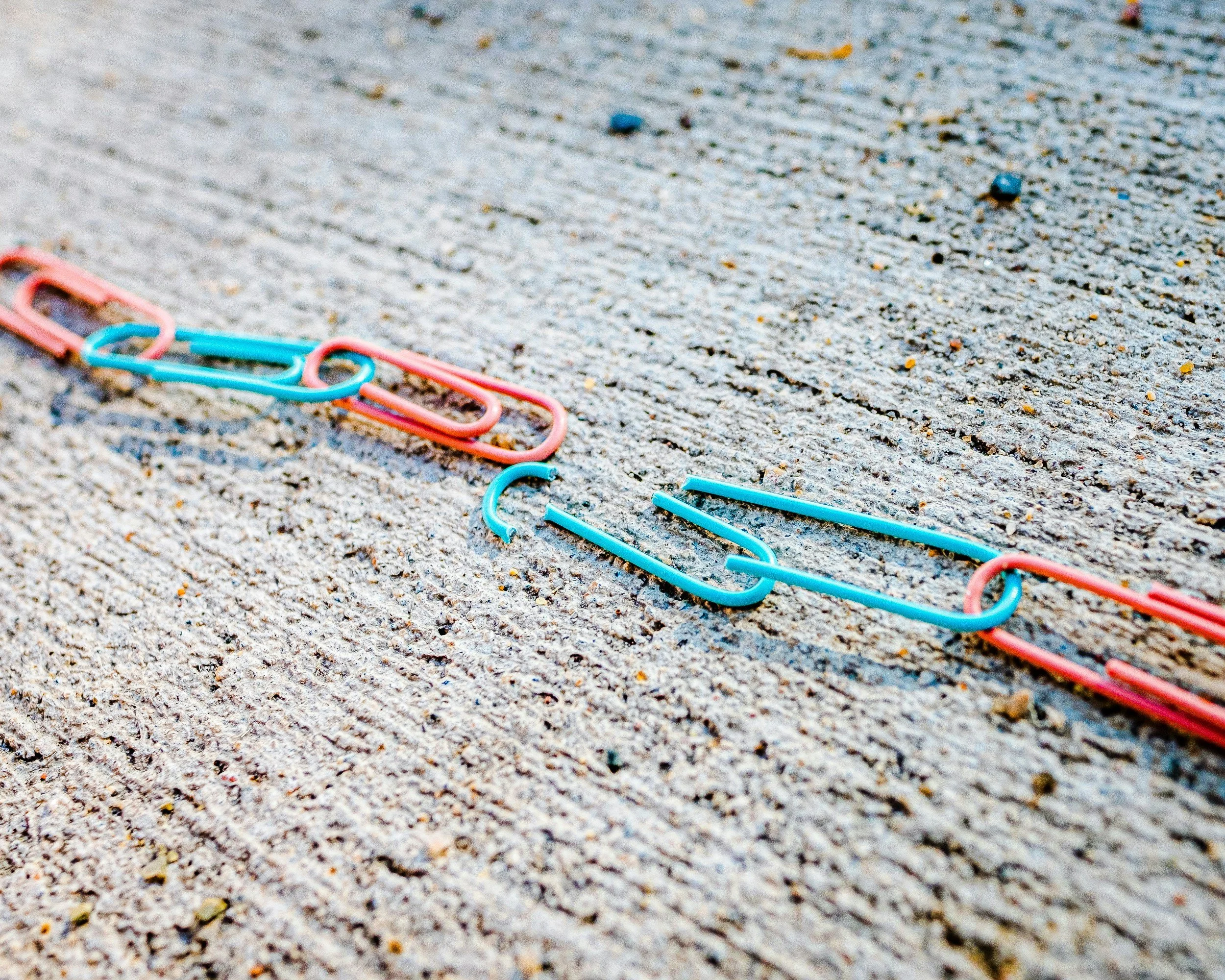 Colorful paperclips scattered on a textured surface.