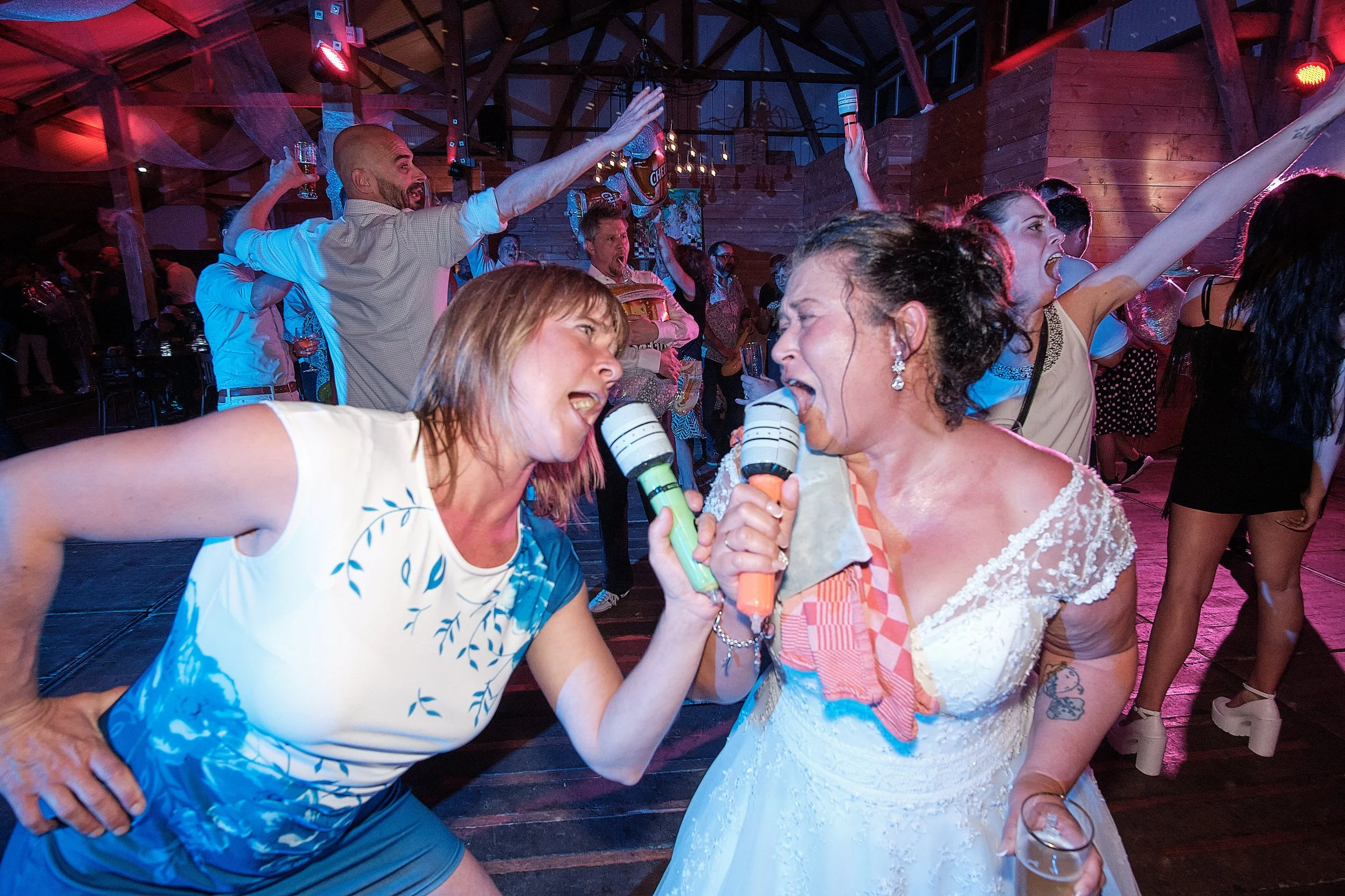 Mensen die zingen en dansen op een feest in een houten locatie.