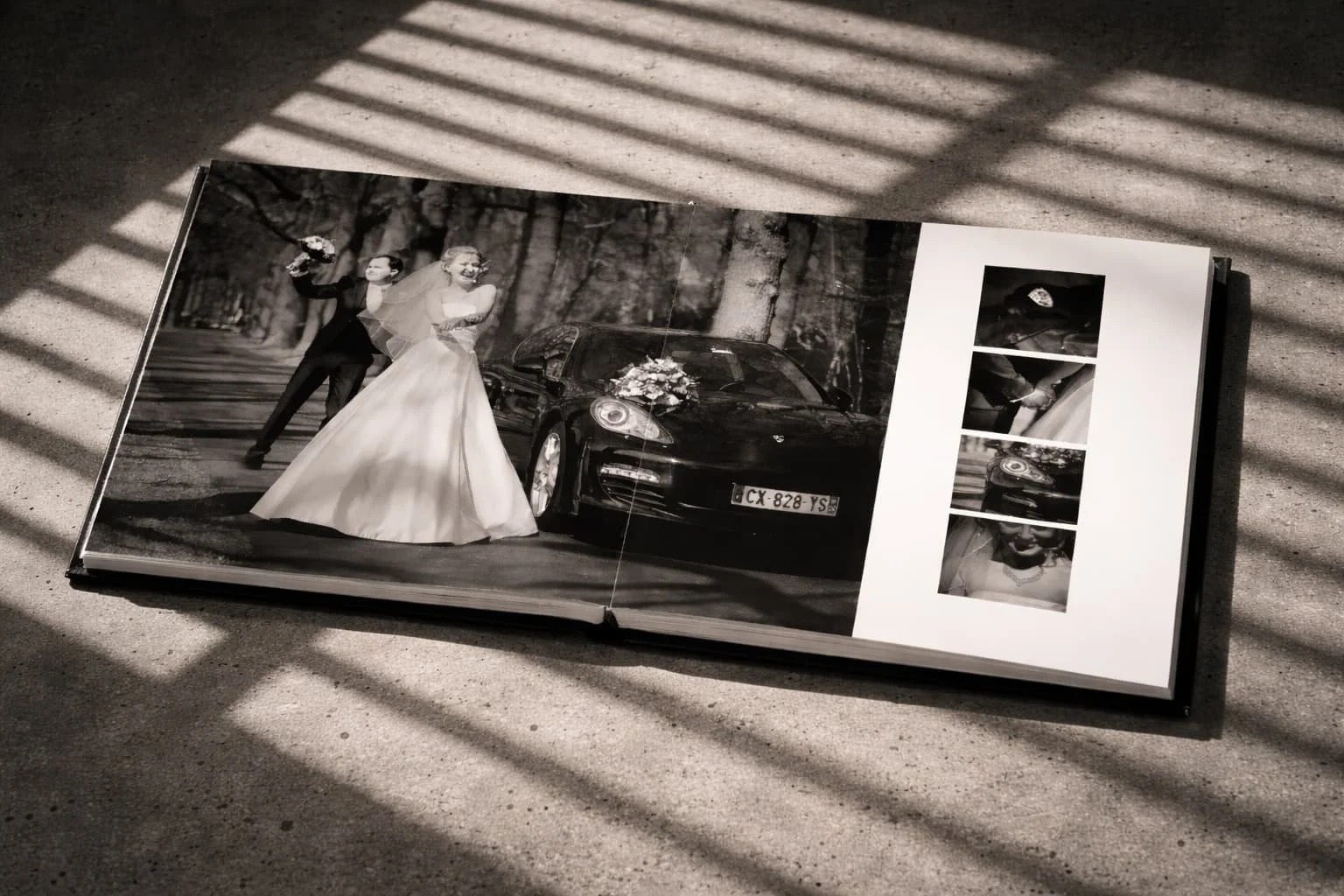 Een zwart-wit foto in een album van een huwelijk, met een bruid en bruidegom voor een auto versierd met bloemen, onder een boom, met enkele kleine foto-inserts aan de rechterkant.