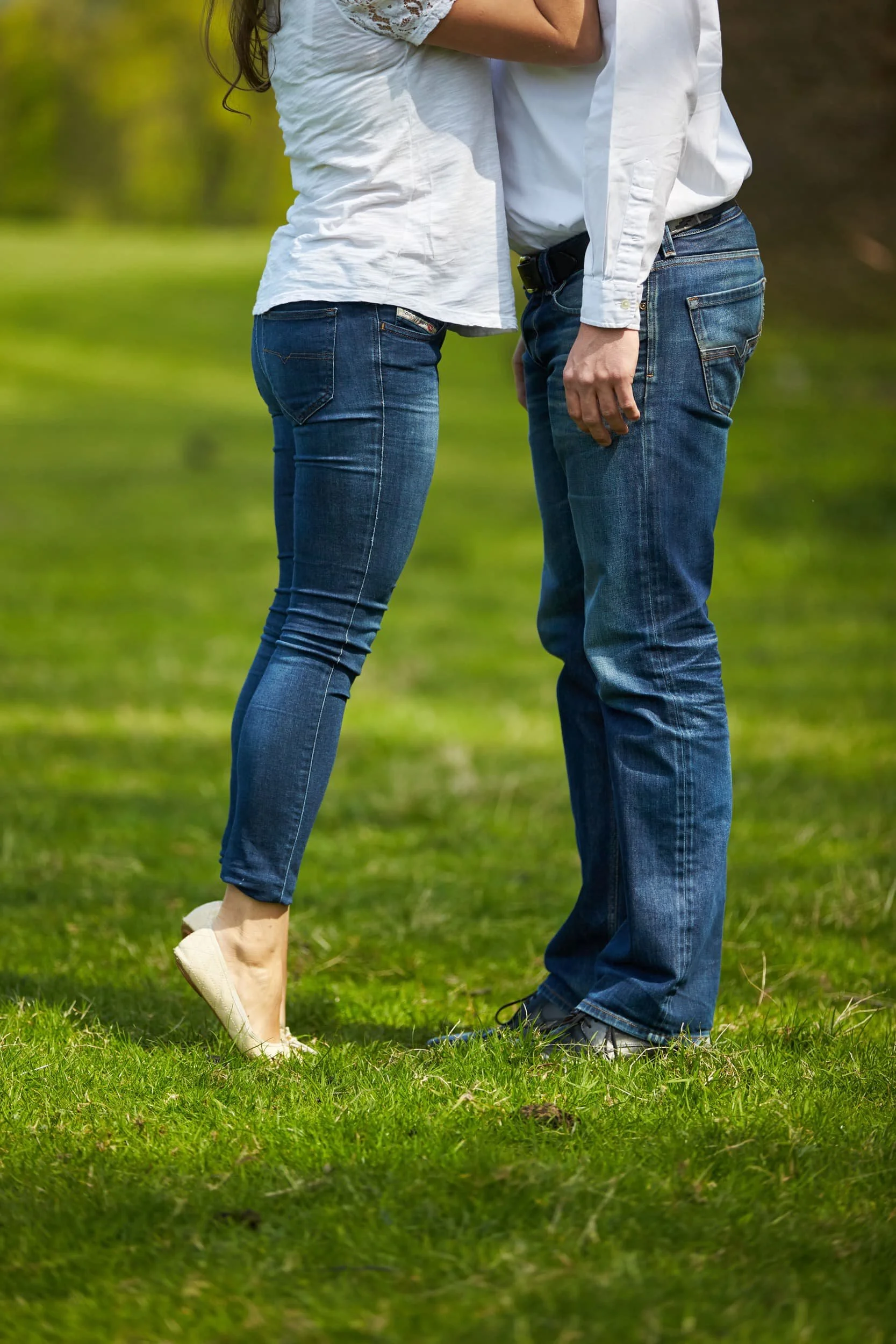 Close-up van een paar dat elkaar in een park vasthoudt, met een groene achtergrond en gras.