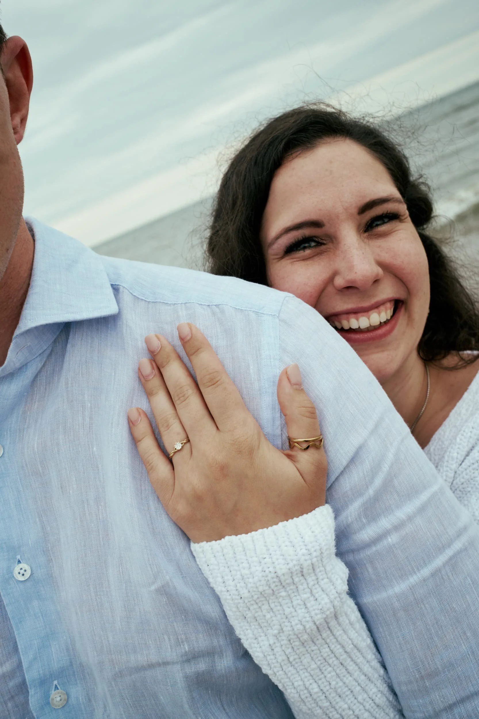 Lachende vrouw die haar hand op de schouder van een man legt op het strand tijdens de dag.
