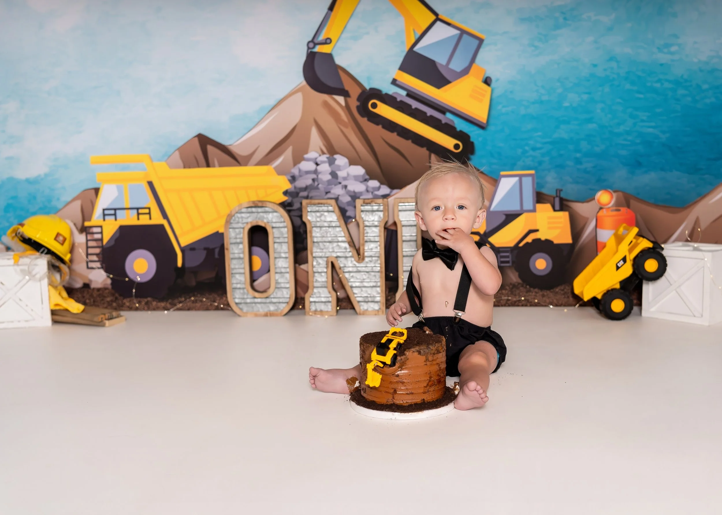 Sweet 1st birthday cake smash photography session in studio showing baby boy with construction theme