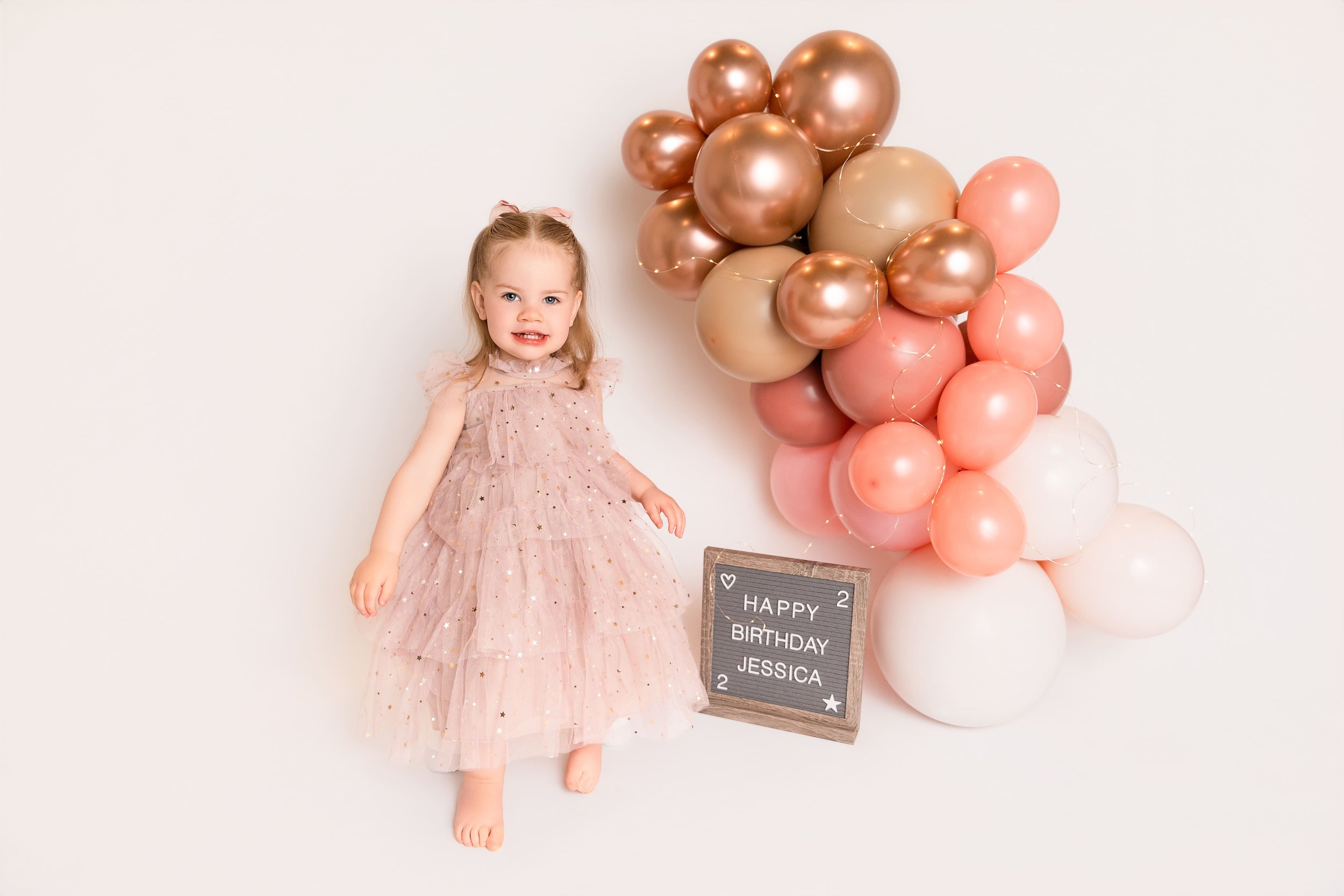 toddler girl in pink dress at birthday photoshoot in a studio in Canton, GA