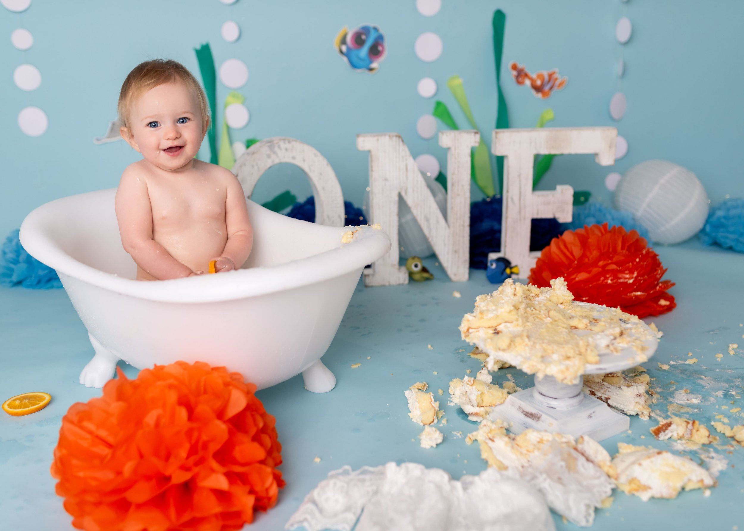 image of little baby after a cake smash taking a fruit bath in a baby sized claw foot tub