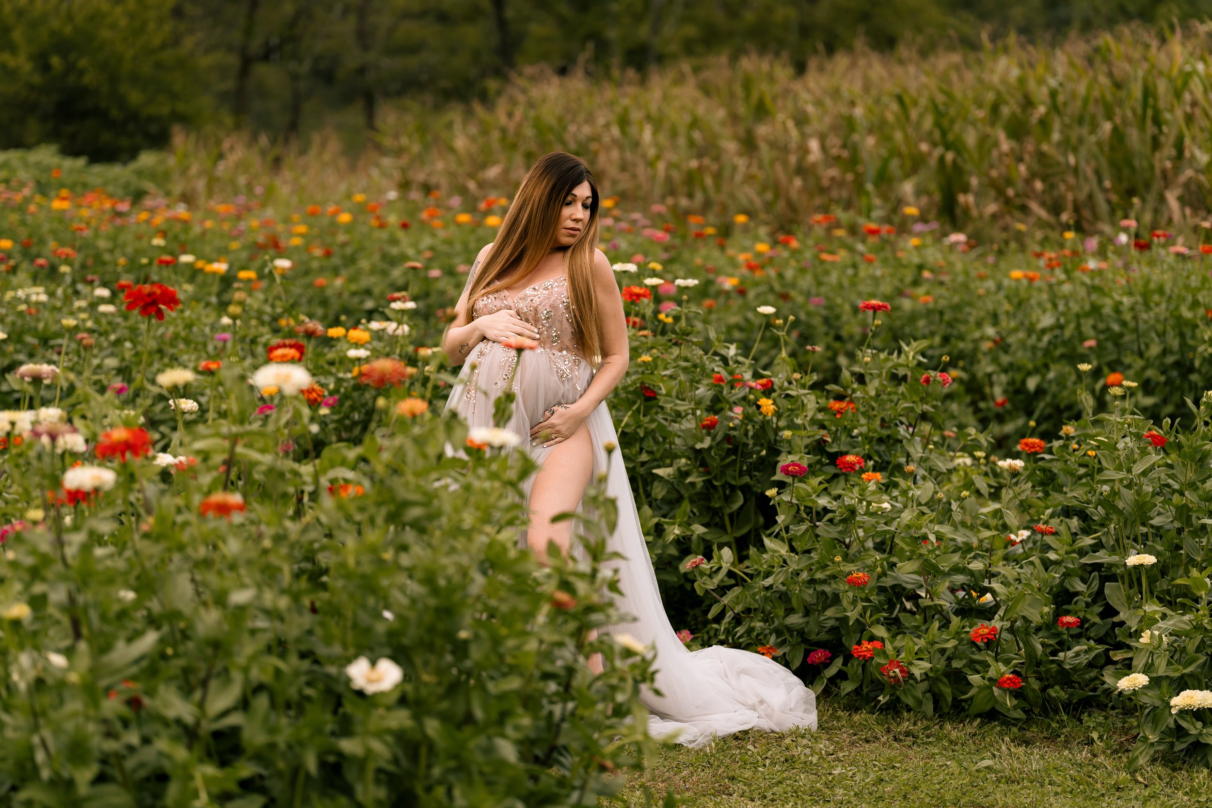 beautiful expectant mother in a flower field wearing a maternity gown highlighting her pregnant belly in Canton, GA