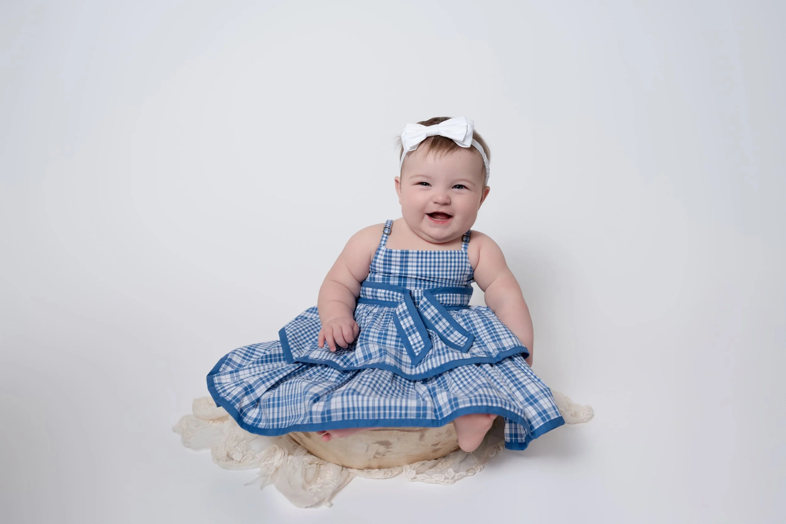 image of baby girl in blue striped dress sitting for her milestone session in Captured Moments by Cindy's photography studio in Canton, GA