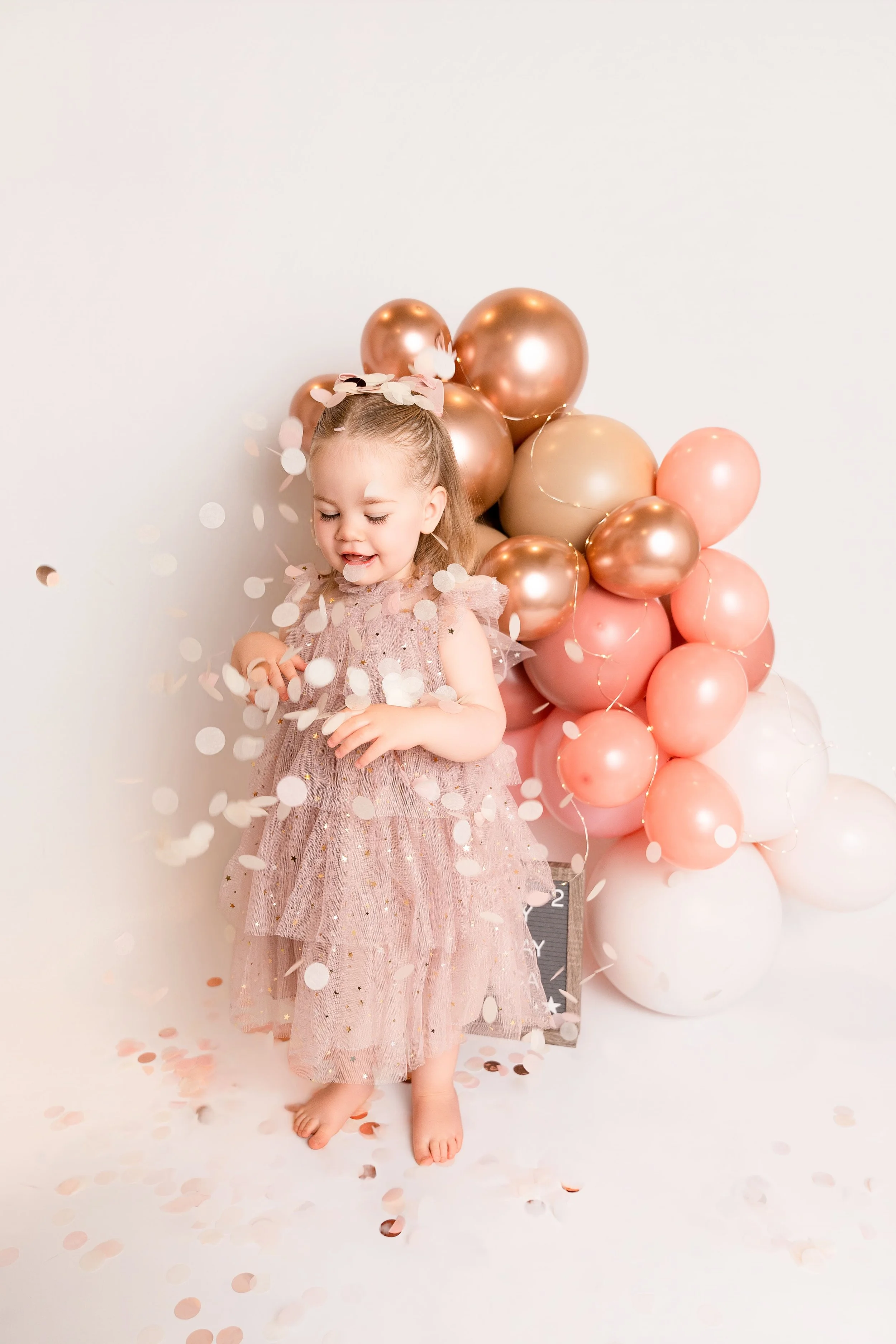 image of little girl in pink dress next to pink balloon garland for a birthday photoshoot in Canton, GA