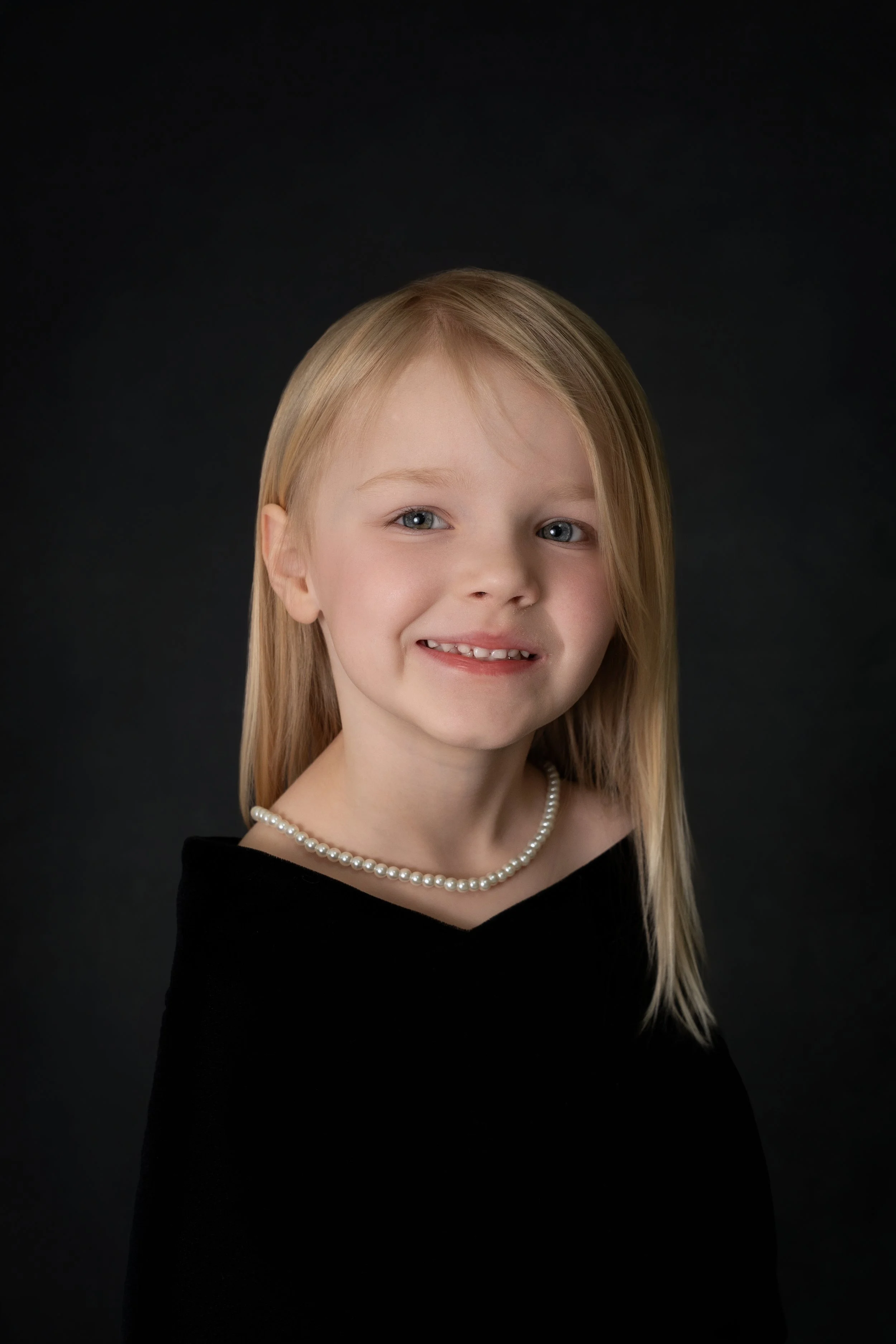 little girl dressed in black drape and pearls for pre-k grad photo