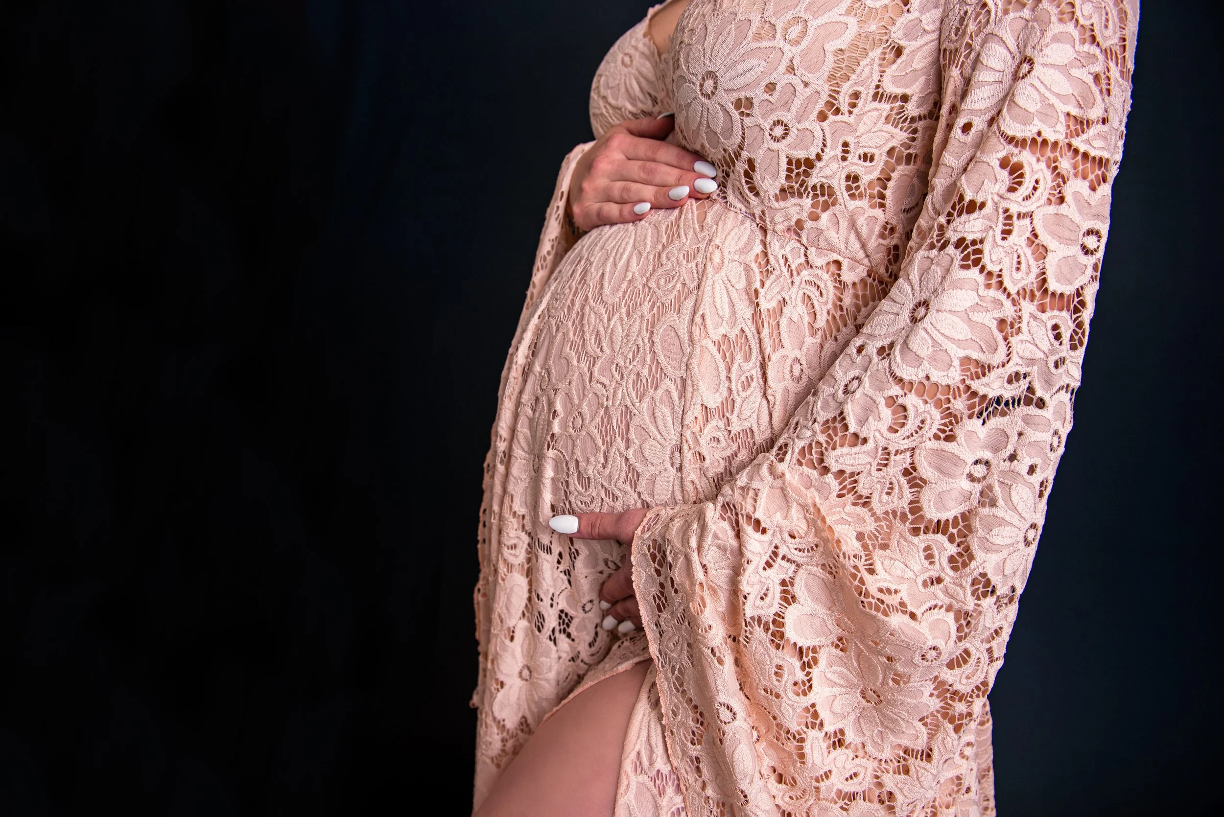 photo of pregnancy mom's belly in a lacy maternity gown posed for a photography session in studio