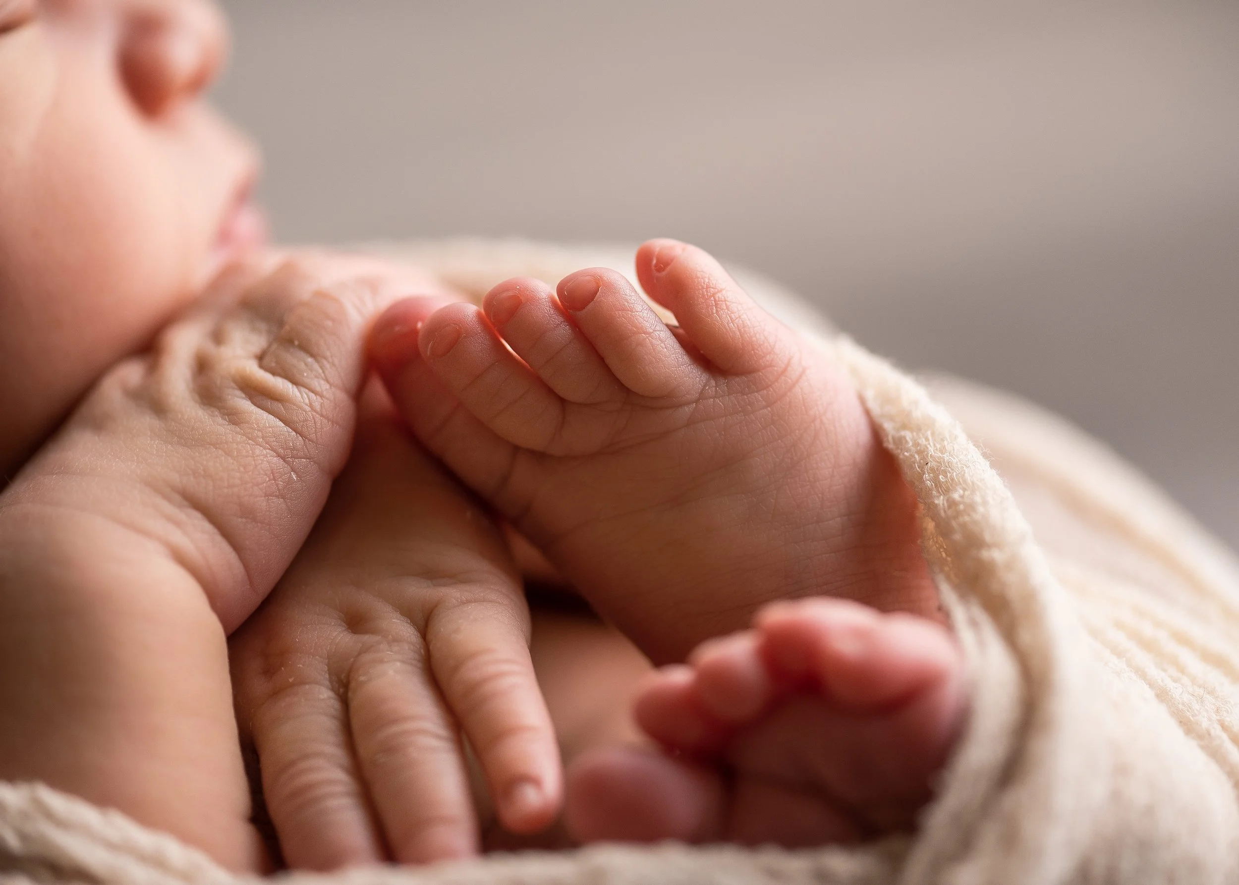 sweet newborn hands and feet of a wrapped newborn baby in a studio session in Canton, GA