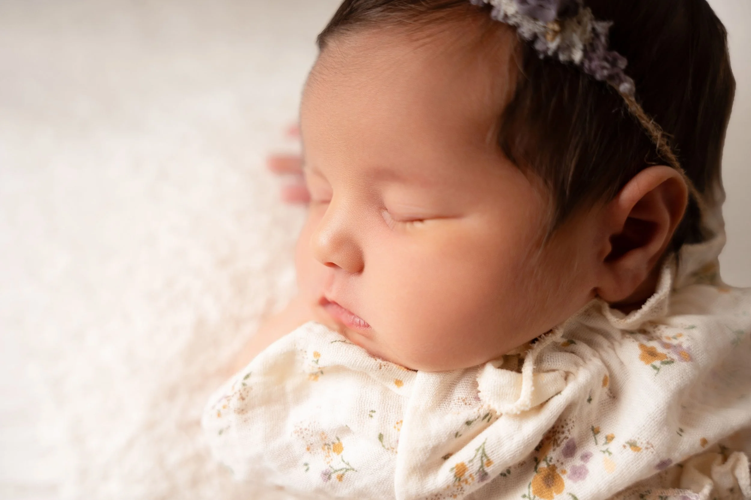 sweet baby photoshoot showing a wrapped newborn baby posed in photography studio in Canton GA