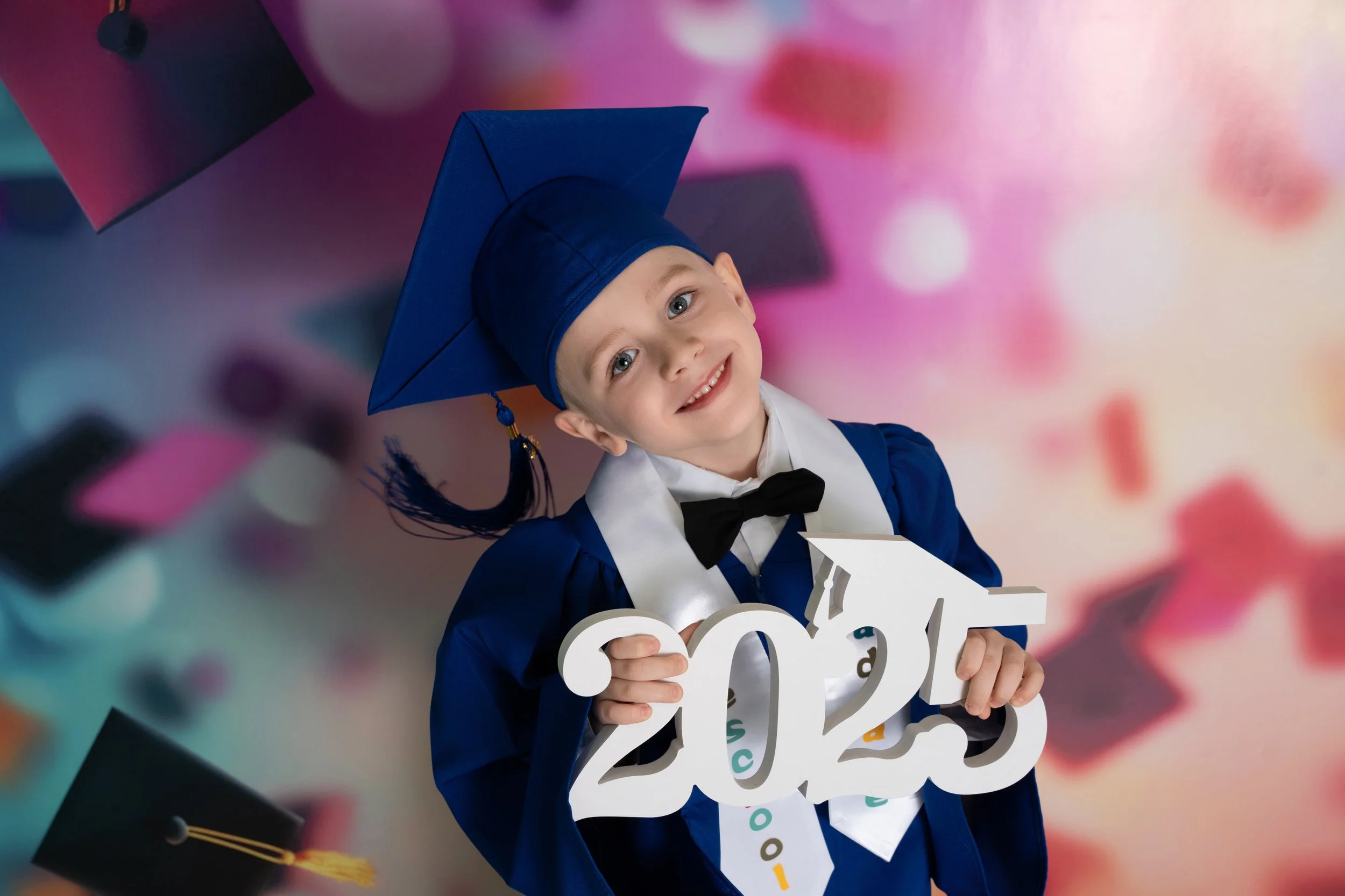 little boy dressed in cap and gown for pre-k grad photo
