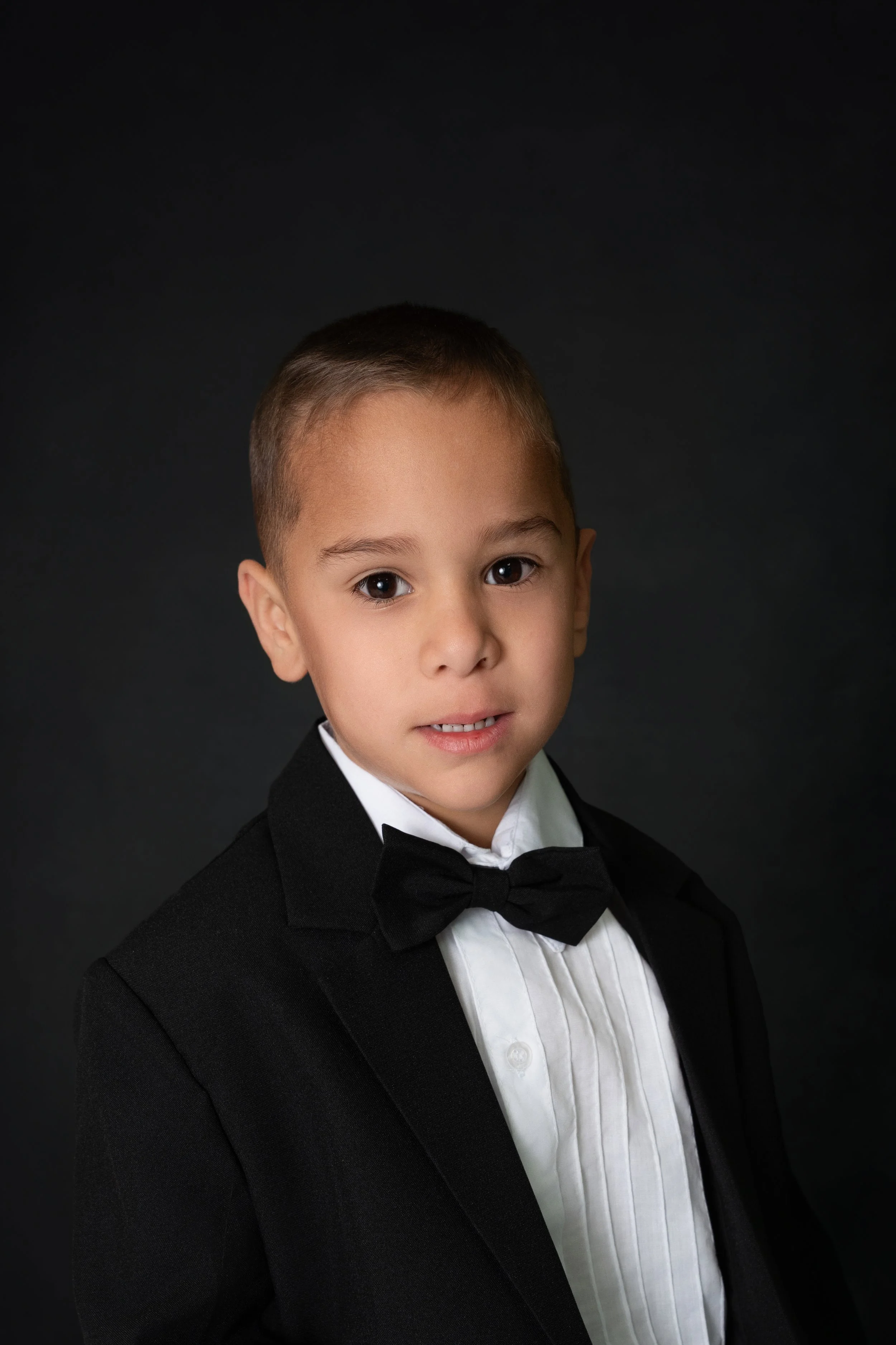 little boy dressed in tux for pre-k grad photo
