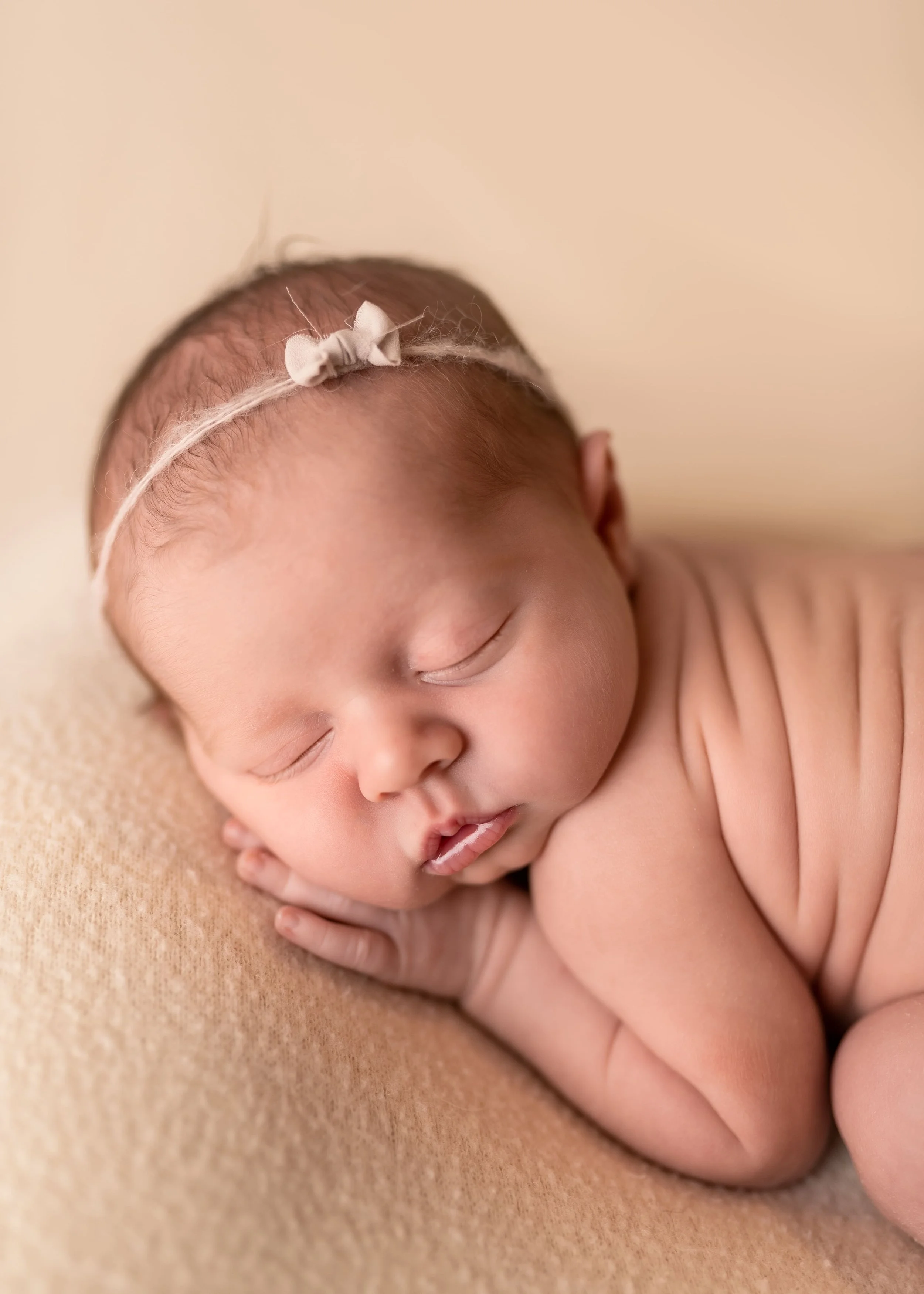 sweet baby photoshoot showing a newborn baby posed on a comfy spot in bum up pose