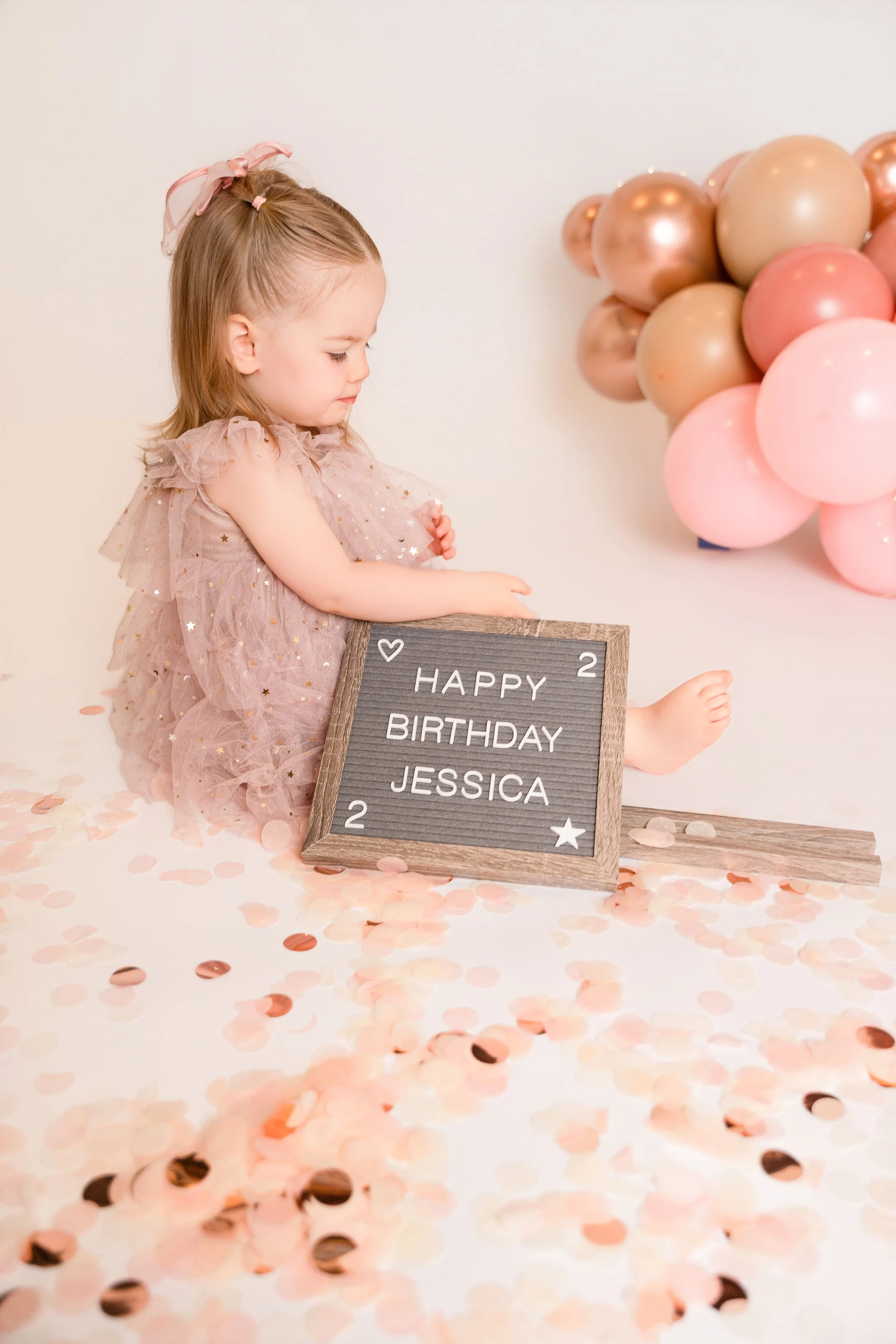 image of little girl in pink dress next to pink balloon garland for a birthday photoshoot in Canton, GA
