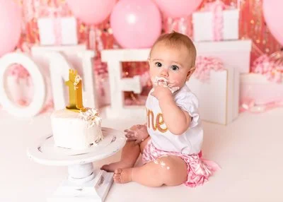 Sweet 1st birthday cake smash photography session in Canton, GA studio of a baby girl with pink and gold theme