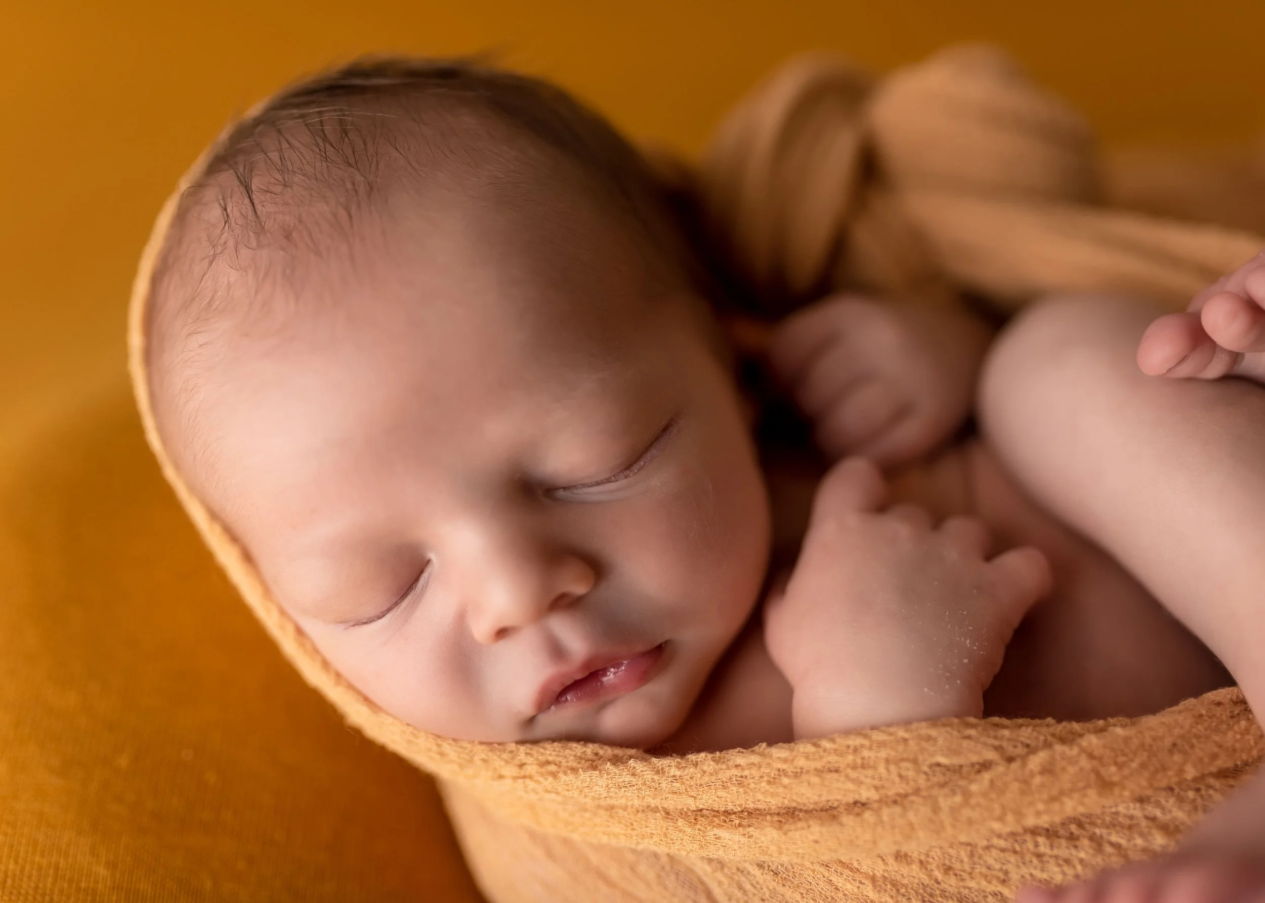 sweet studio photoshoot of a newborn baby wrapped in a yellow wrap in Canton, GA