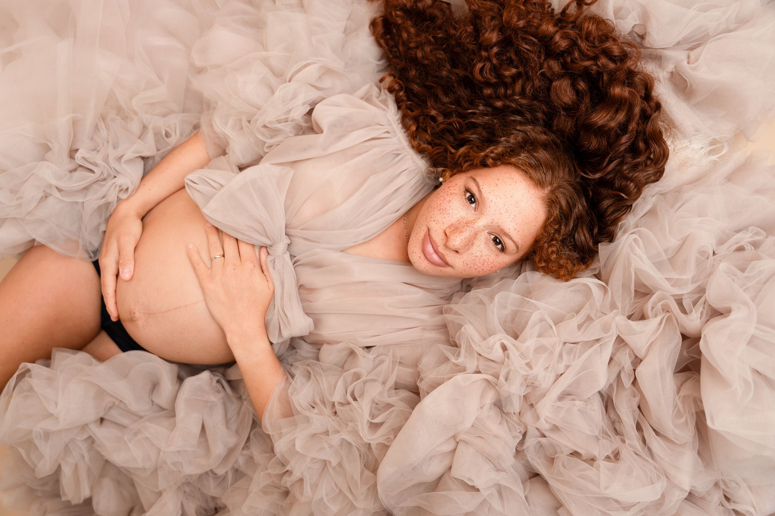 pregnant mother in couture pink ruffly gown posing for maternity photographer in studio in north ga