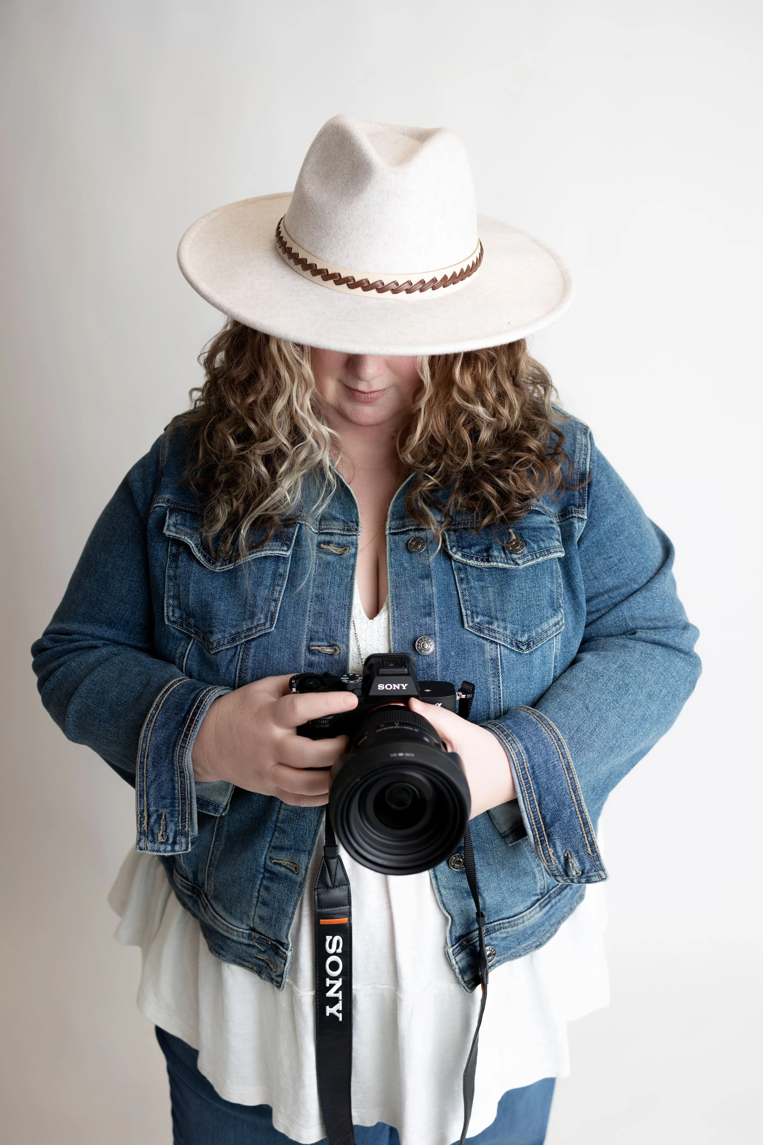 image of Cindy holding her camera in a studio setting on white background