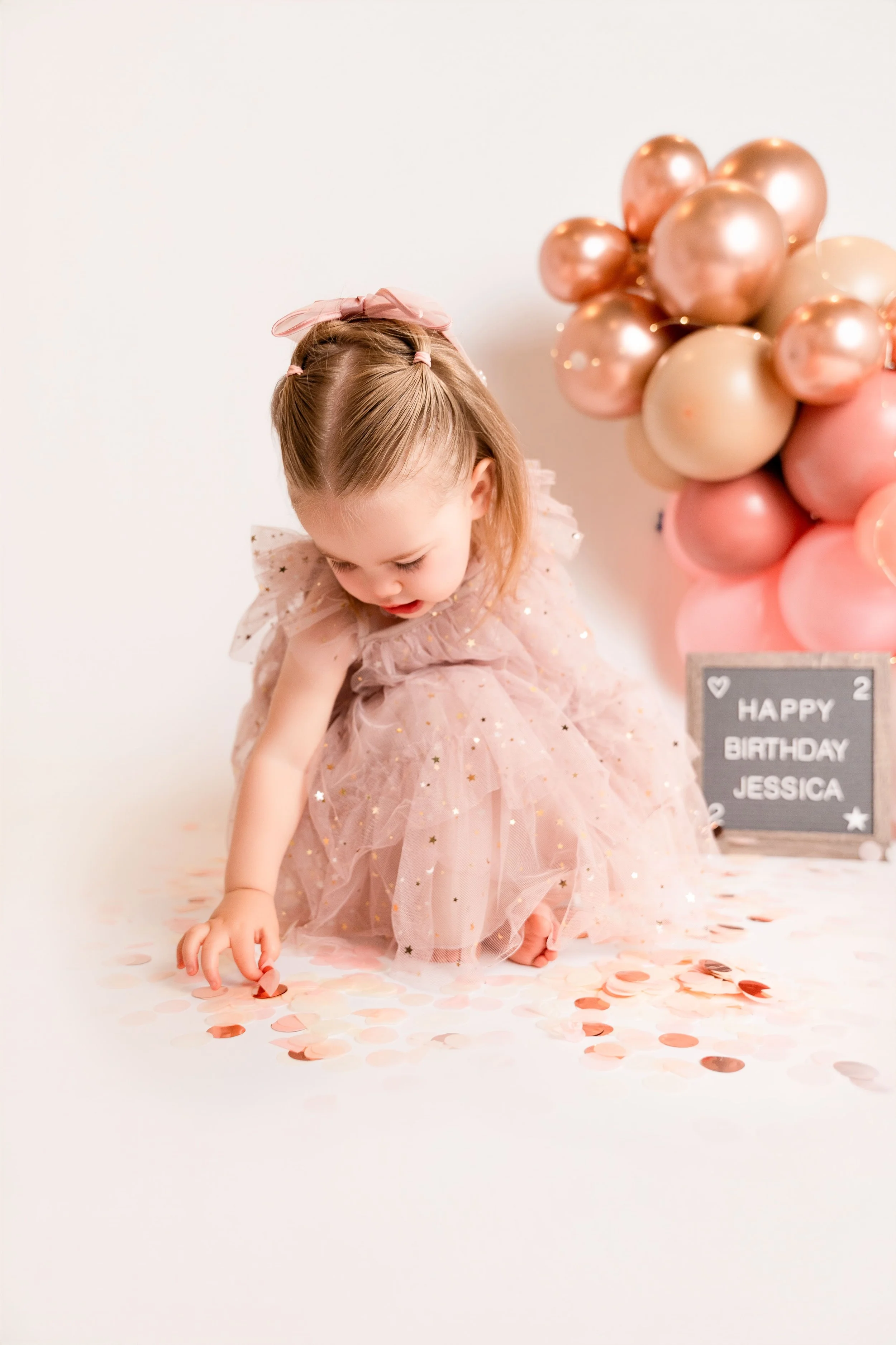 toddler girl in pink dress at birthday photoshoot in a studio in Canton, GA