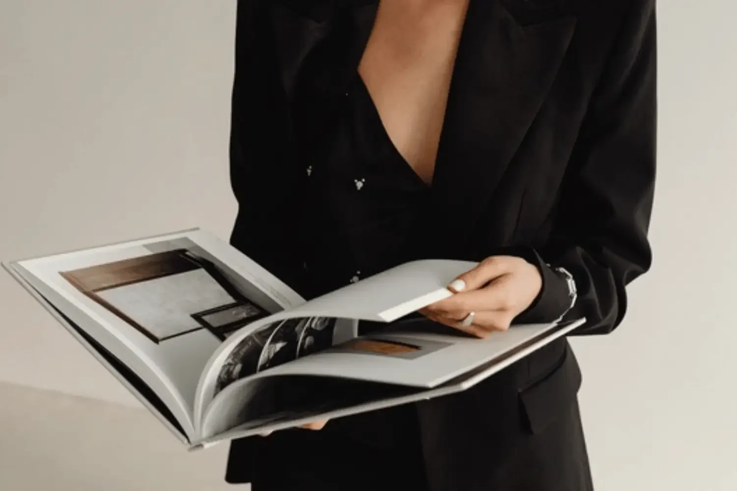 Professional in black blazer reviewing an open book, symbolizing bookkeeping strategy and financial record review