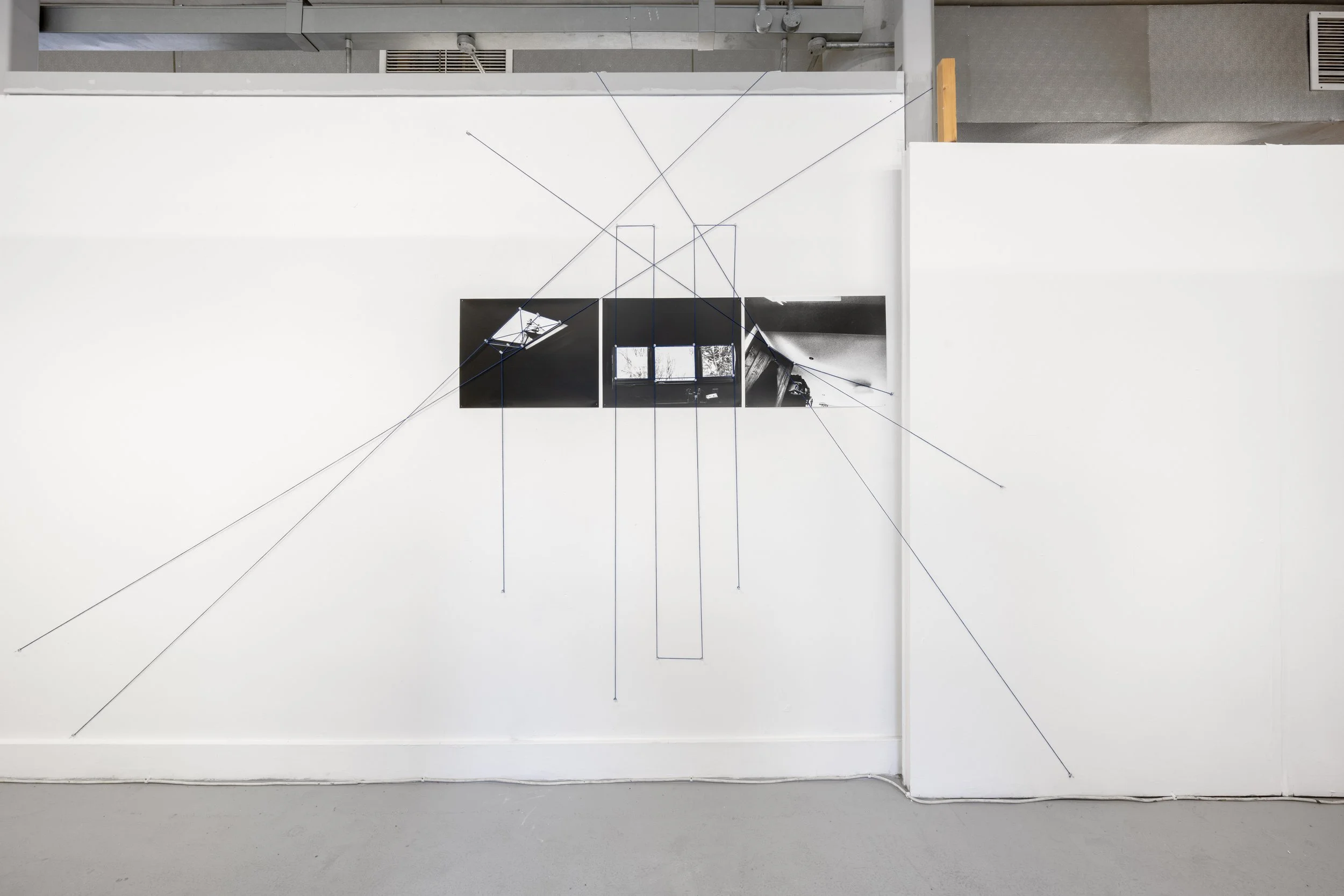 From My Bed Exhibition photograph of Liz Samway's artwork against a white wall in the White Column gallery. The artwork comprises three separate black & white photographs, linked and covered with an overlaying network of webbed blue thread that conti