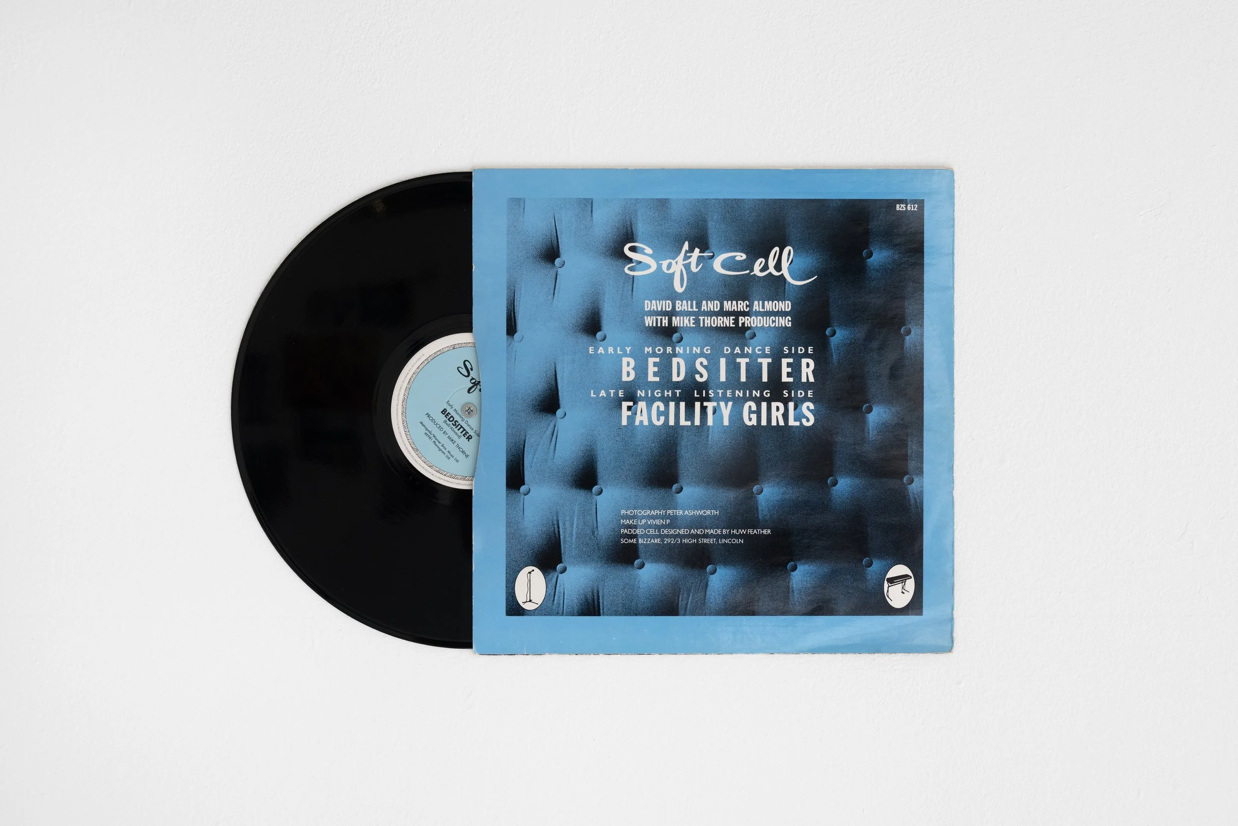 Peter Ashworth's artwork photographed against a white wall in the White Column space. The back of a 12” record sleeve featuring a close-up of an image of a pale-blue bed mattress, strong lighting from the left to increase shadows on the right to acce