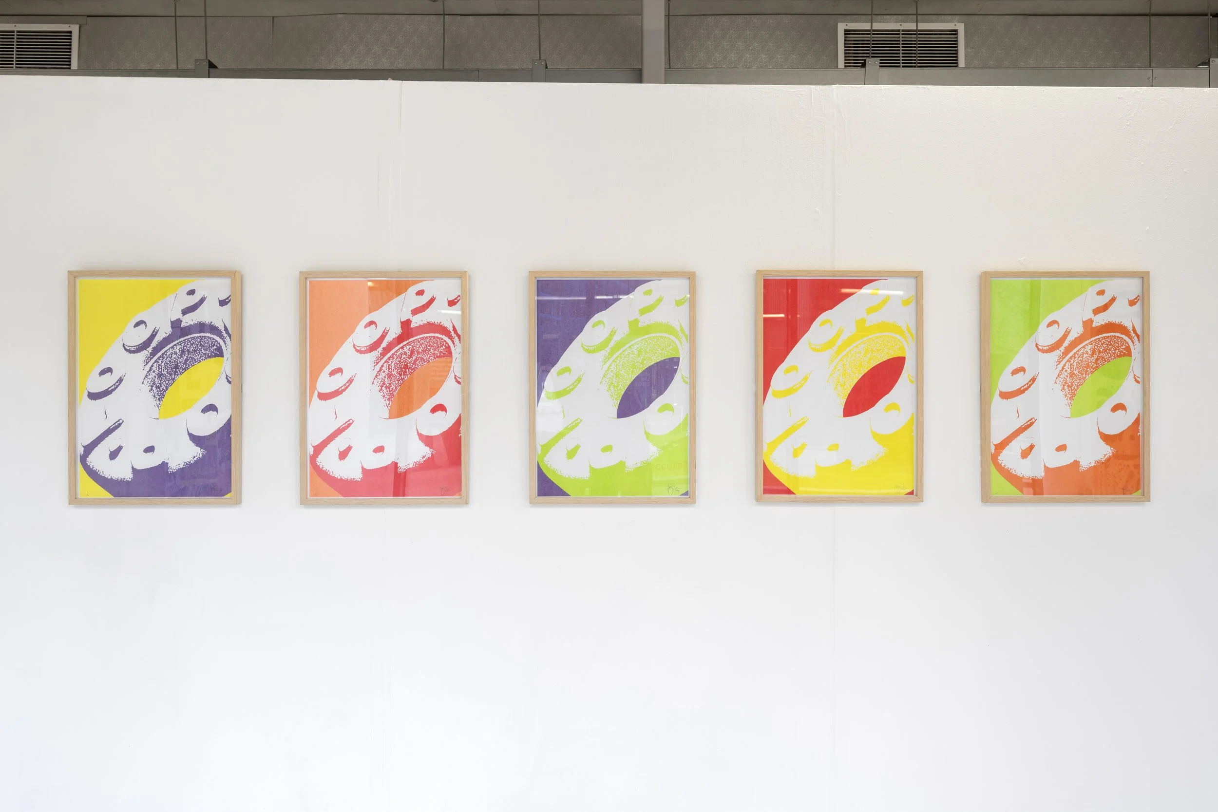 Exhibition photograph of a series of five multi-coloured prints in different bold colours, each depicting the same image of an enlarged ‘Fruit Loop’ sweet (a variant of a mint POLO). The fruit loop is inscribed with ‘Loop’ filling majority of the fra