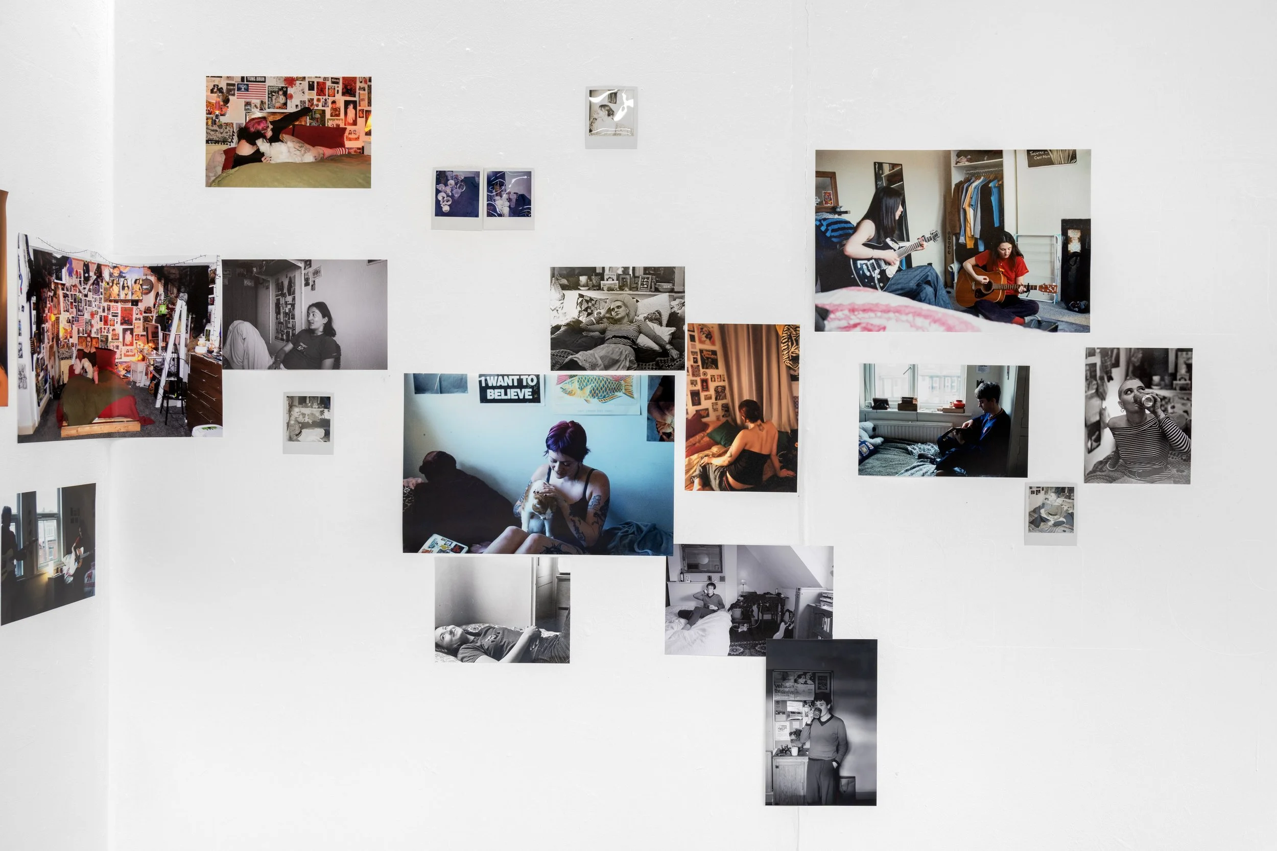 Image of Abbie Bruff's ‘Between Panic and Pleasure’ installed in ‘From my Bed’ exhibited in the corner of the white walled gallery. A photographic installation incorporating an array of images in both black and white and colour. Installed in a scatte