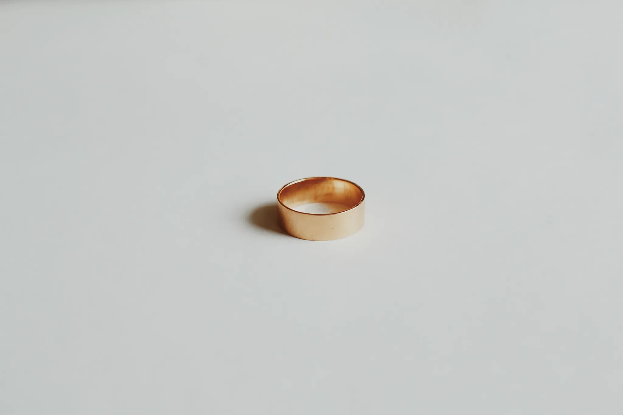 A wedding band lying in the middle of white nothingness