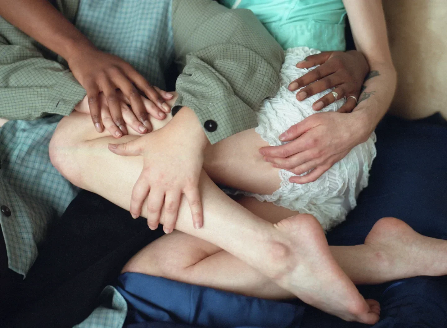 3 people with no faces shown sit and hug on a couch