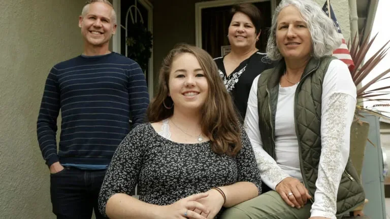 A family with 3 adults and one child photographed at a porch