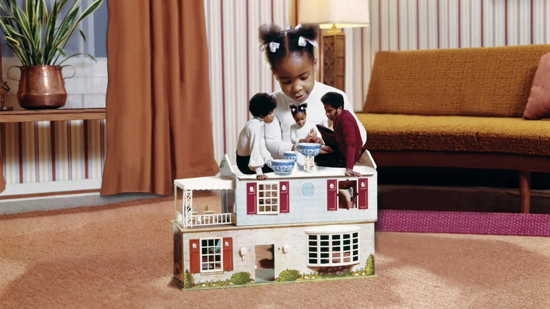 A montage of a little girl playing with a toy house where a version of herself and her parents are having a pretend tea party