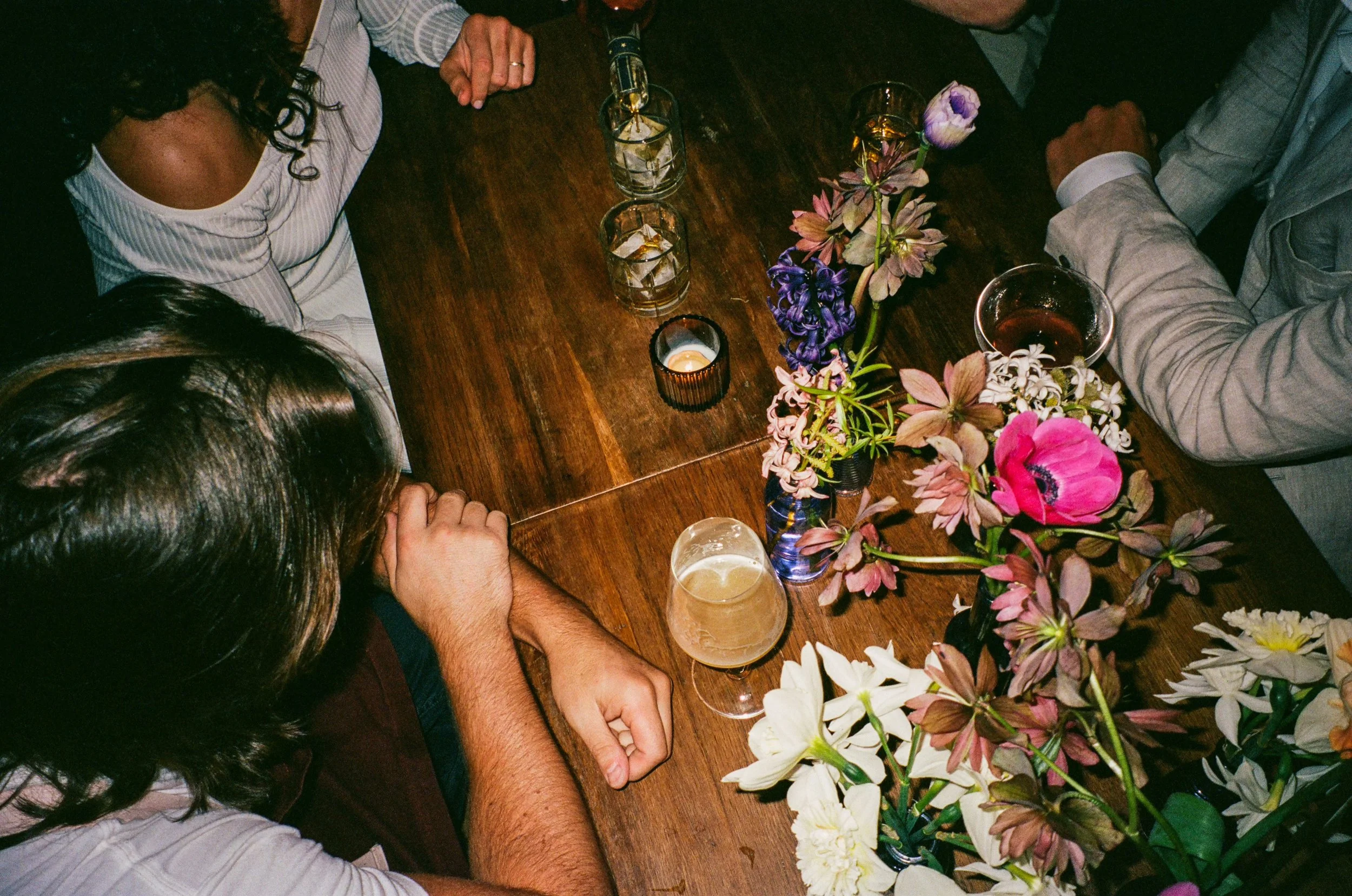 People sitting around a wooden table with flowers and drinks at Ethos Wine Bar & Bistro in Downtown Nantucket
