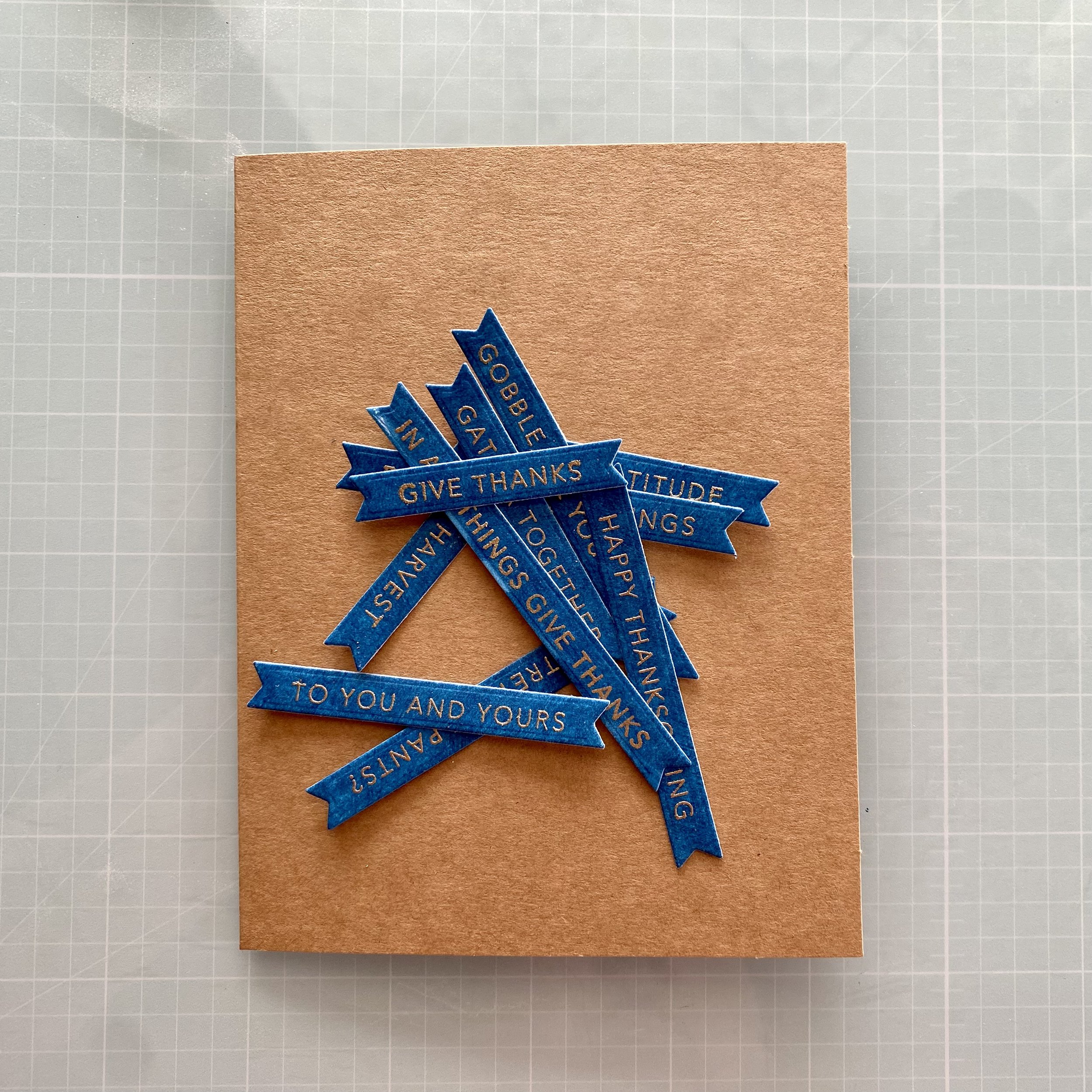 A Kraft card base with a little pile of blue sentiment strips on top.