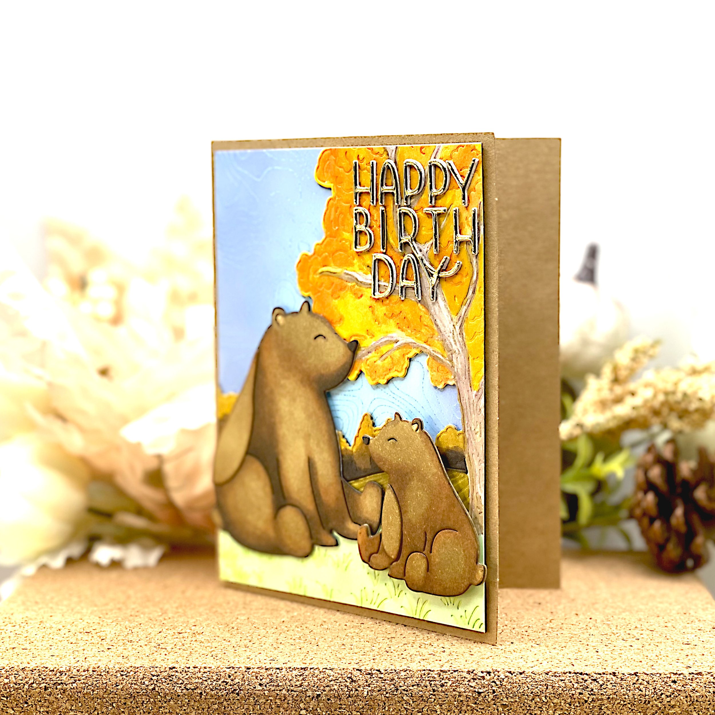 Birthday card with mama bear and bear cub in autumnal landscape