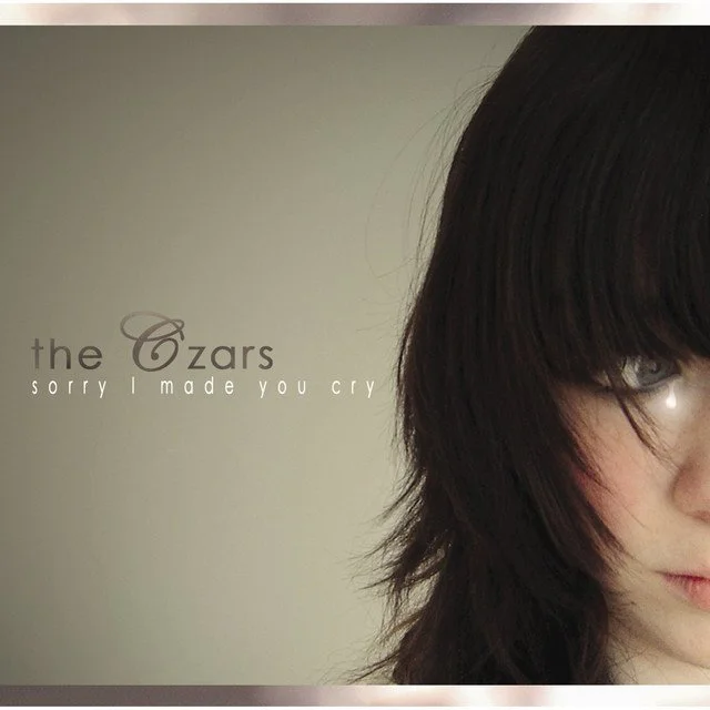 Close-up of a young woman's face with dark hair on the right side of the image, and the left side contains text reading 'the Czars sorry I made you cry' against a plain background