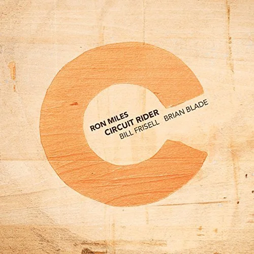 A circular wooden sign with a cut-out section, displaying the names Ron Miles, Circuit Rider, Bill Frisell, and Brian Blade.