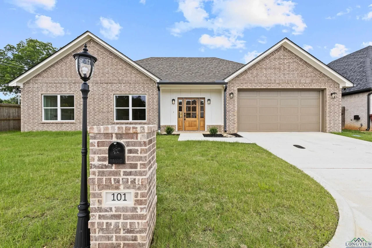 Brick house with front lawn, mailbox, street lamp, and driveway