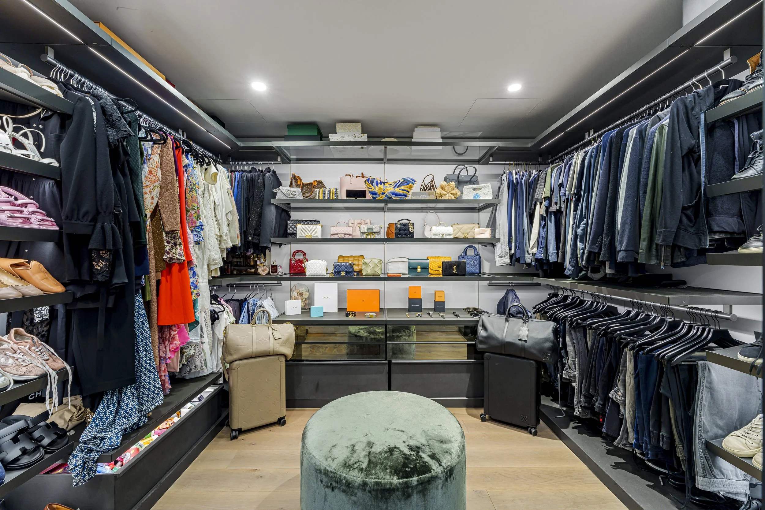Clothing and handbag store with shelves of bags and clothing racks on both sides, a seating area in the center.