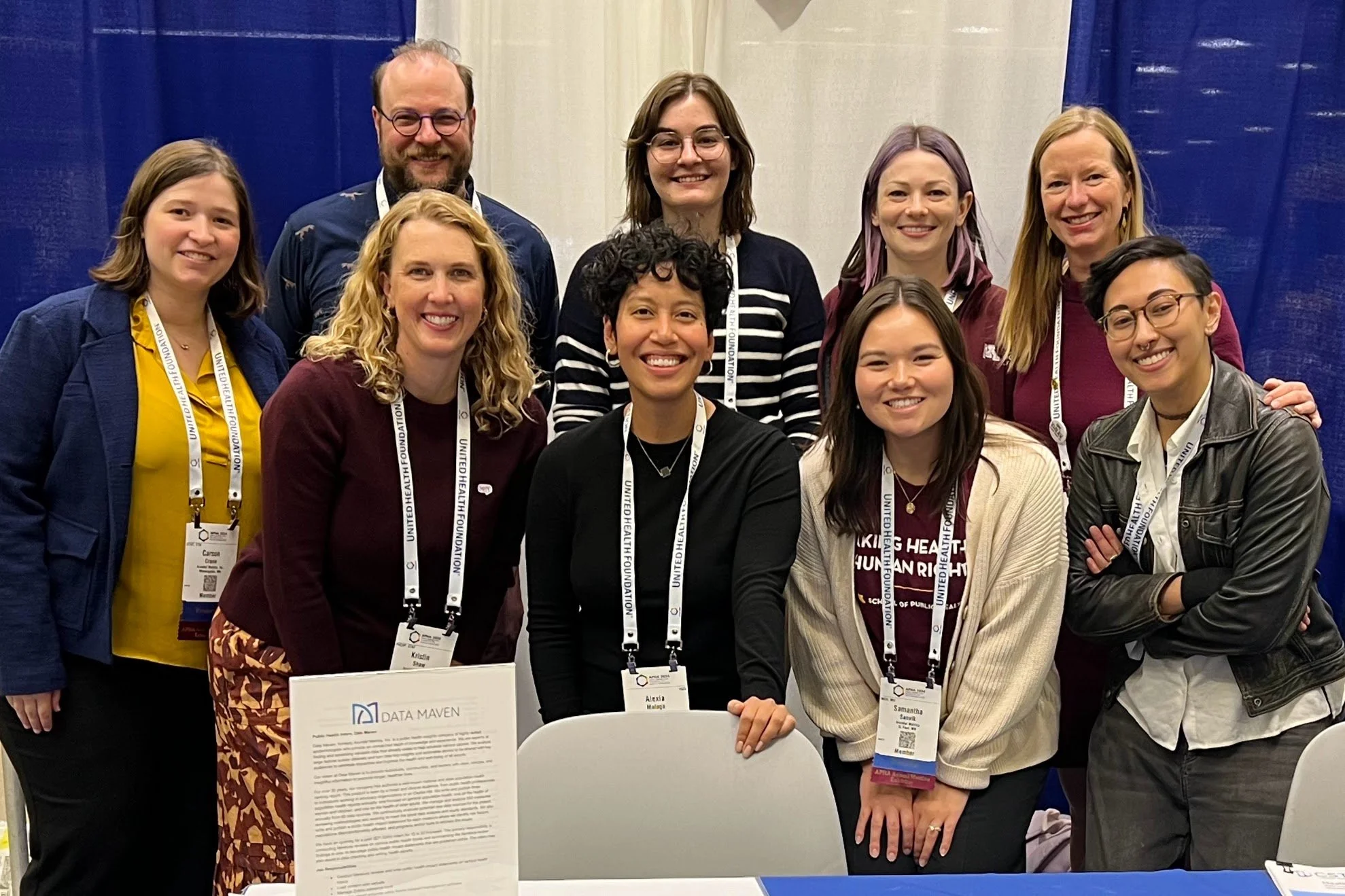 Team members gathered, wearing conference badges and smiling.