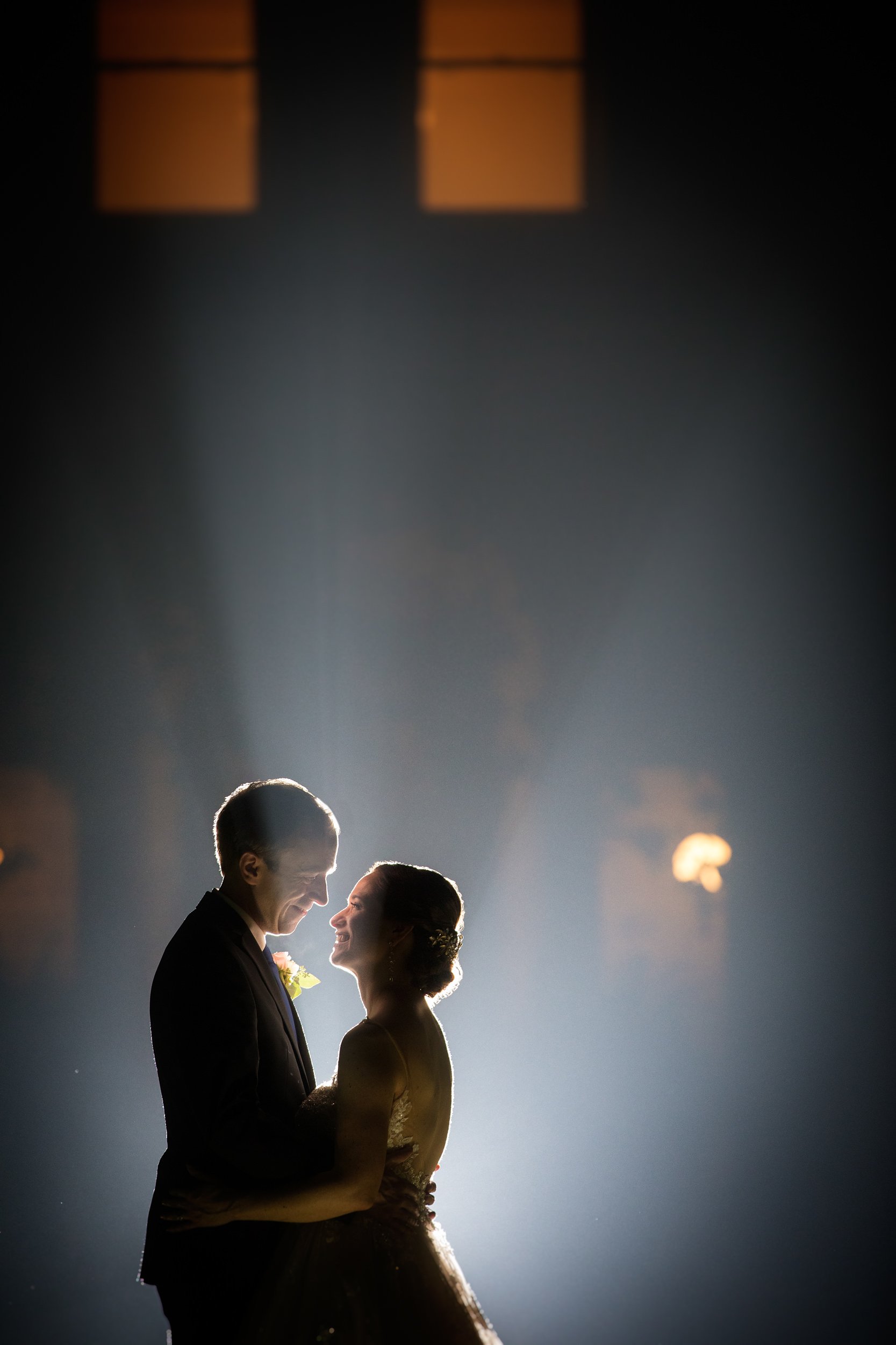 A couple embraces foggy night air for a romantic embrace on their wedding day.