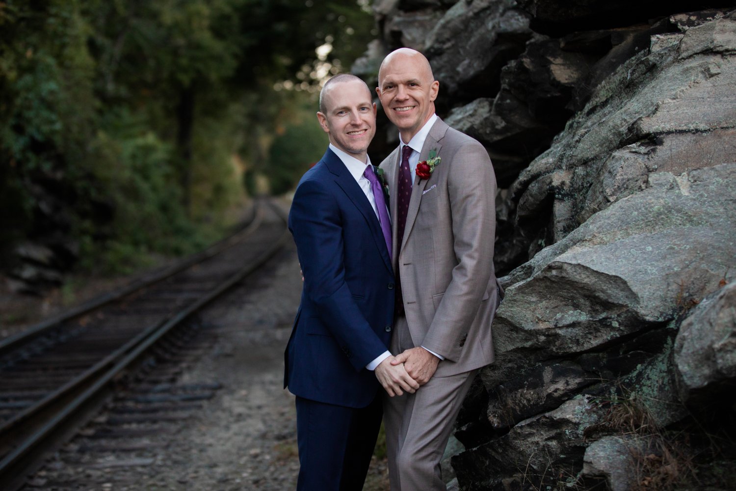 Two grooms hold hands in a sweet and gentle embrace at their Essex, CT wedding